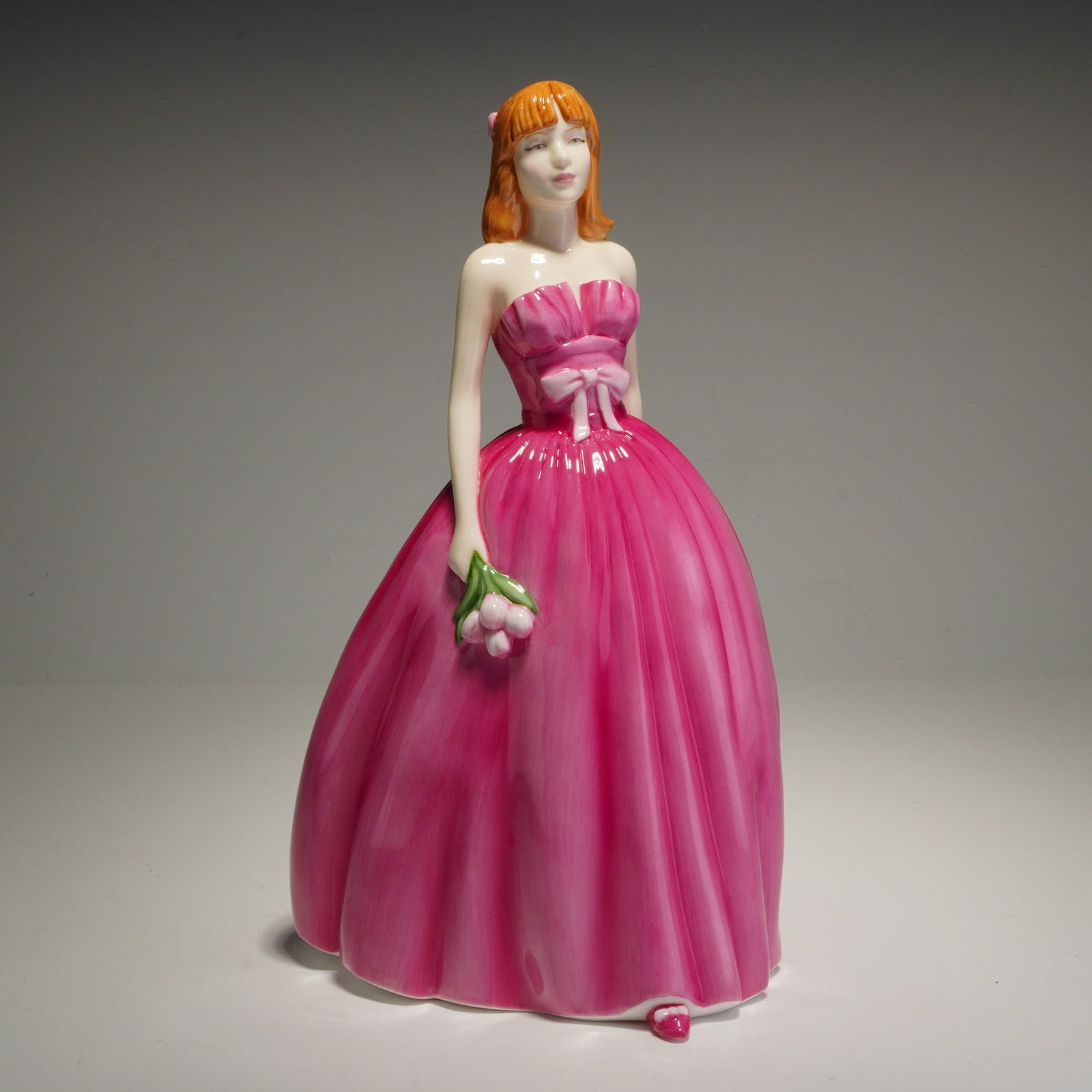Royal Doulton Pretty Ladies Figurine, From the Heart HN4895: This Royal Doulton figurine, titled From the Heart (HN4895), is a part of the Pretty Ladies series designed by Nada M. Pedley. The piece is composed of hand-made and hand-decorated bone china. The fig