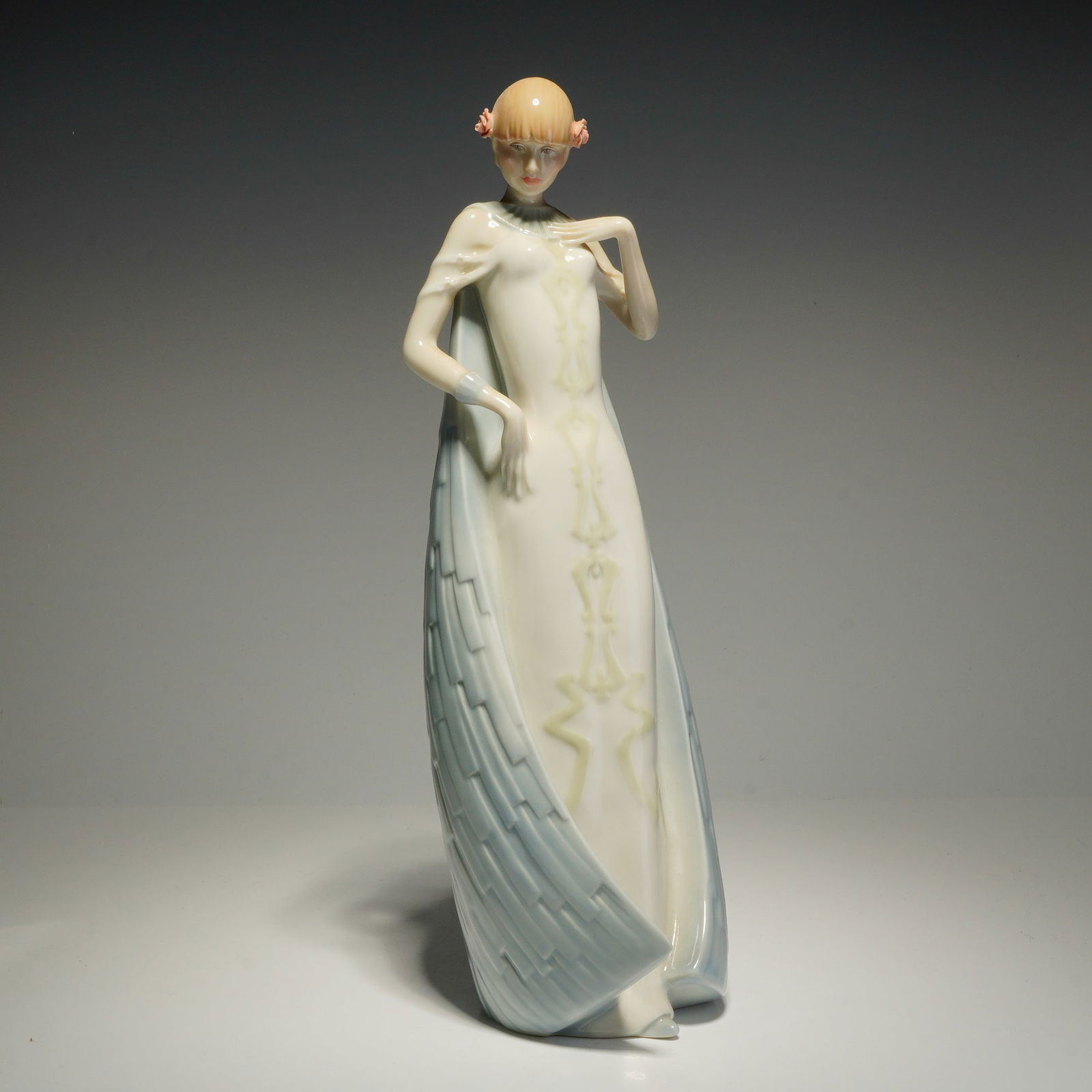 Royal Doulton Reflections Figurine, Debut HN3046: This Royal Doulton figurine, titled Debut (HN 3046) from the Reflections series, was modeled by P. Parsons and is dated 1985. The subject is depicted in a cream-colored gown with a central vertical de