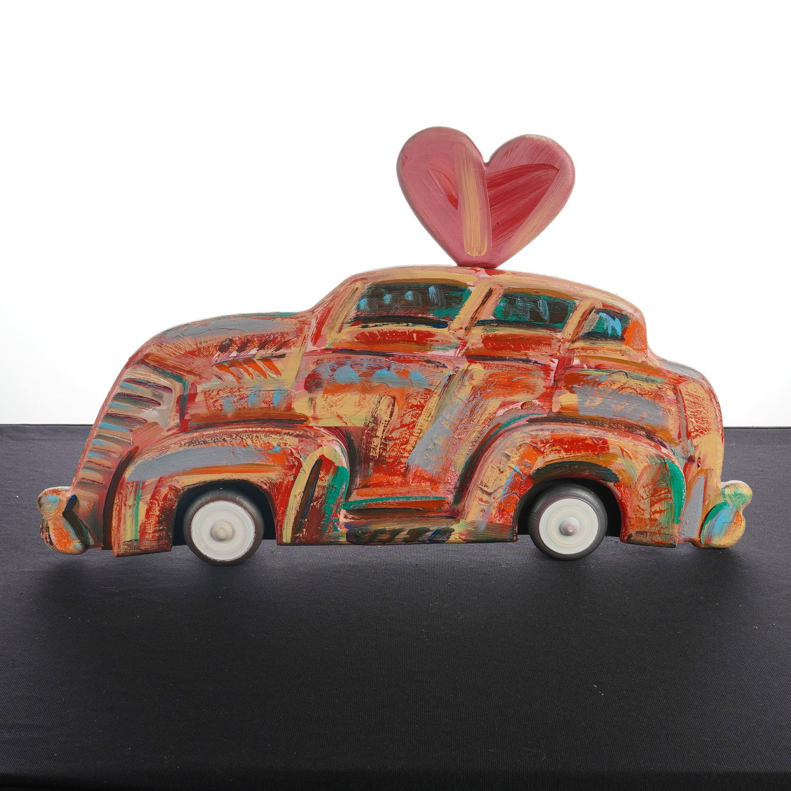 Frank Romero, Carro con Corazon, Oil Painted Wood Sculpture, Signed: Frank Romero (Mexican-American, b. 1941), Carro con Corazon (Car with Heart). This hand-carved wooden sculpture depicts a vintage sedan finished in oil paint. The object features a polychrome surface
