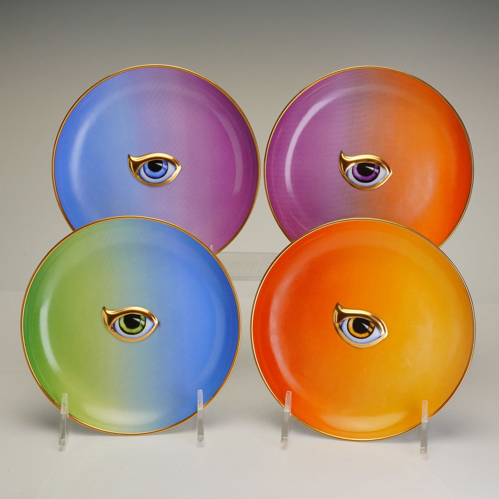 Set of Four L'Objet Lito Plates, Multi-Color Eye: This set of L'Objet Lito plates consists of four porcelain canape or dessert plates featuring a surrealist eye theme. Each circular plate is decorated with a central eye motif featuring high relief wo