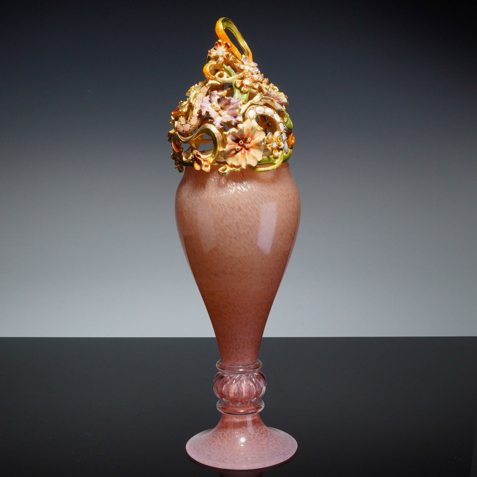 Jay Strongwater Polly Bouquet Lidded Potpourri Vase: A Jay Strongwater lidded potpourri vase in the Polly Bouquet pattern. The vessel features a tapered body of pink aventurine blown glass with gold-tone flecks, supported by a flared foot with a clear r