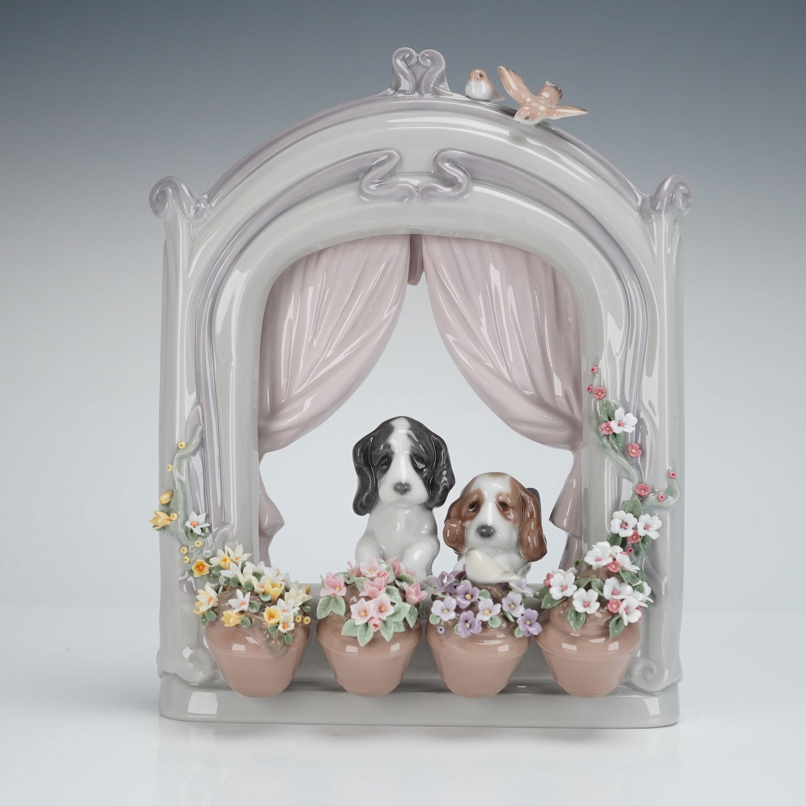 Lladro Please Come Home Figurine 6502: A single Lladro Porcelain Figurine titled Please Come Home!, model number 6502. This hand-made Spanish porcelain group depicts two spaniel-type puppies looking out from a stylized, arched window frame