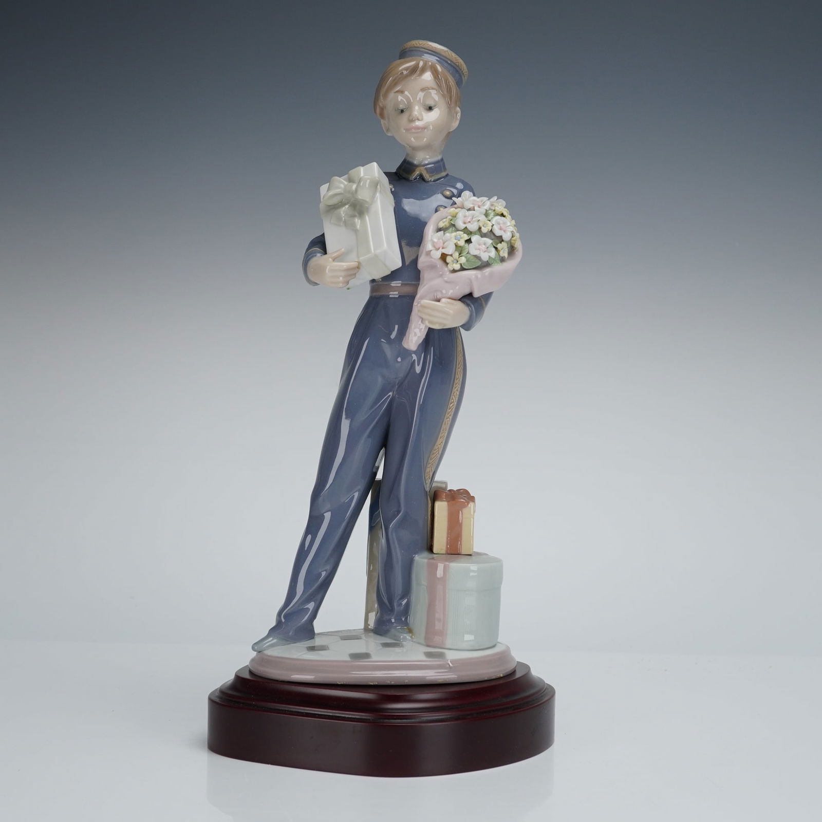 Lladro Special Delivery Figurine 5783: A Lladro porcelain figurine, model number 5783, titled "Special Delivery." The glazed porcelain figure depicts a young post or delivery worker wearing a glossy slate-blue uniform detailed with golden
