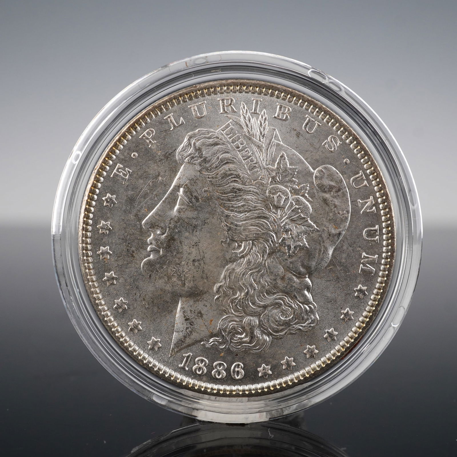 1886 Morgan Silver Dollar Coin: This 1886 Morgan Silver Dollar features two iconic designs. The obverse shows the Liberty head, facing left, with the inscription E A PLURIBUS A UNUM, LIBERTY, and the year 1886 below. The reverse
