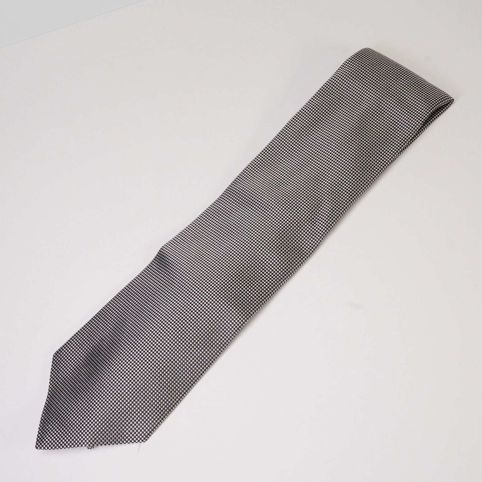 Fioravanti New York Black and White Silk Necktie: A classic Fioravanti New York silk necktie featuring a fine black and white geometric pattern. The tie is crafted from a smooth woven silk fabric, offering a subtle sheen and elegant texture. A