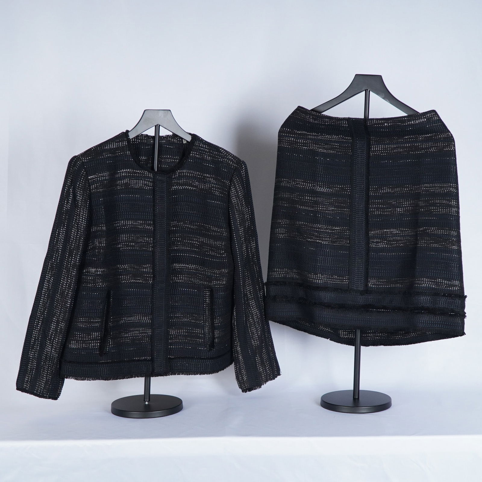 Tahari Black Tweed Skirt Suit: Sophisticated skirt suit featuring a modern open-front jacket crafted in a textured black woven tweed with subtle metallic threading and tonal striping. The jacket includes clean lines, a round