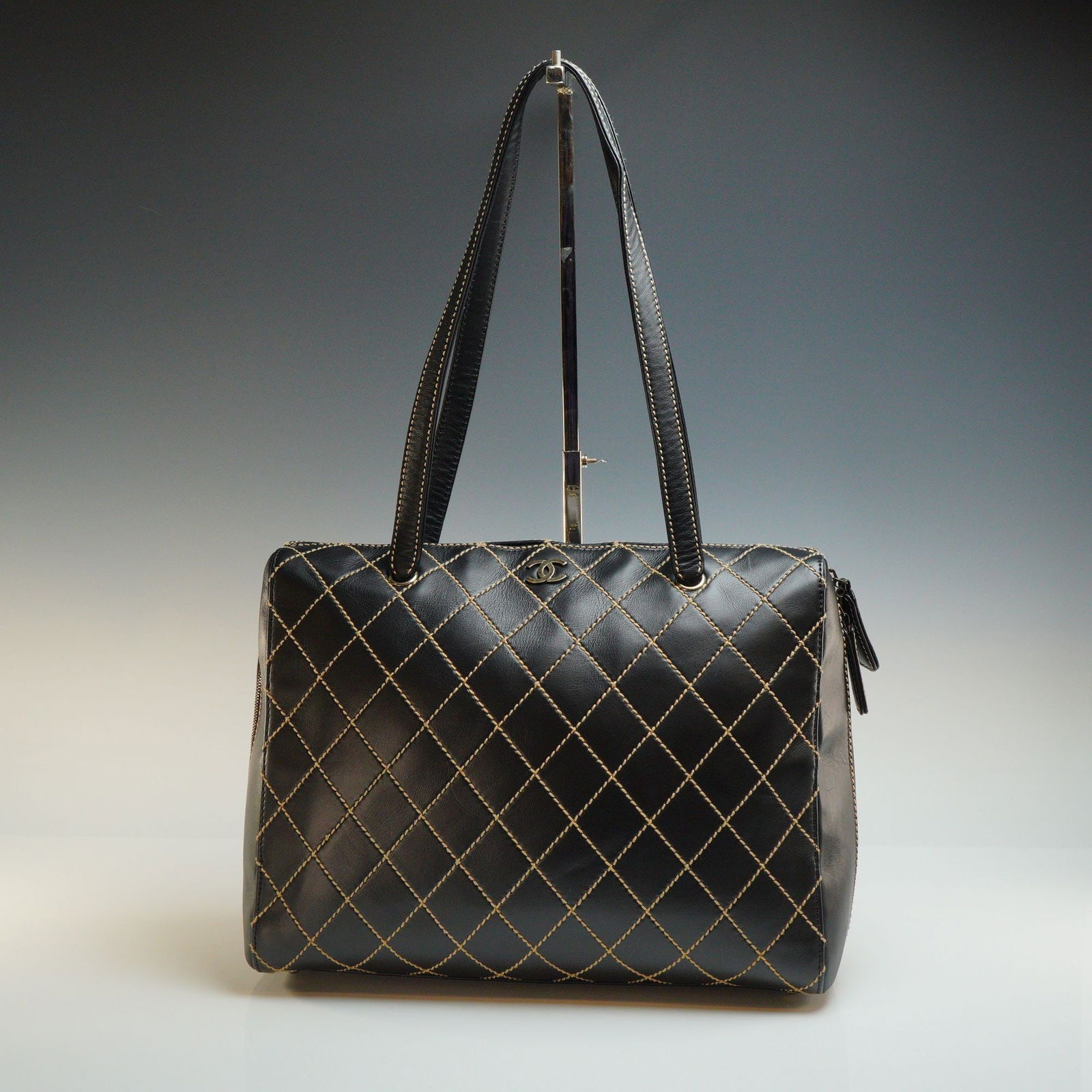 Chanel Black Calfskin Leather Wild Stitch Traveling Bag: A Chanel Wild Stitch traveling bag crafted in black calfskin leather featuring contrasting beige diamond-patterned topstitching. The rectangular form is accented with a gold-tone interlocking CC logo