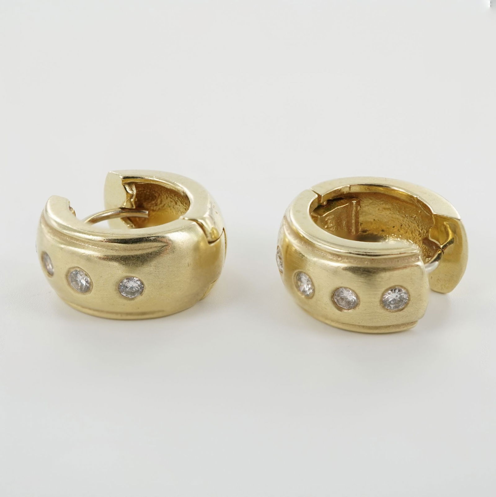 14K Gold and Diamond Hoop Earrings: Each earring features four round diamonds set in a slightly domed gold hoop, marked 14K on the inner hinge. The stones are flush set within the gold surface, adding subtle brilliance to the smooth