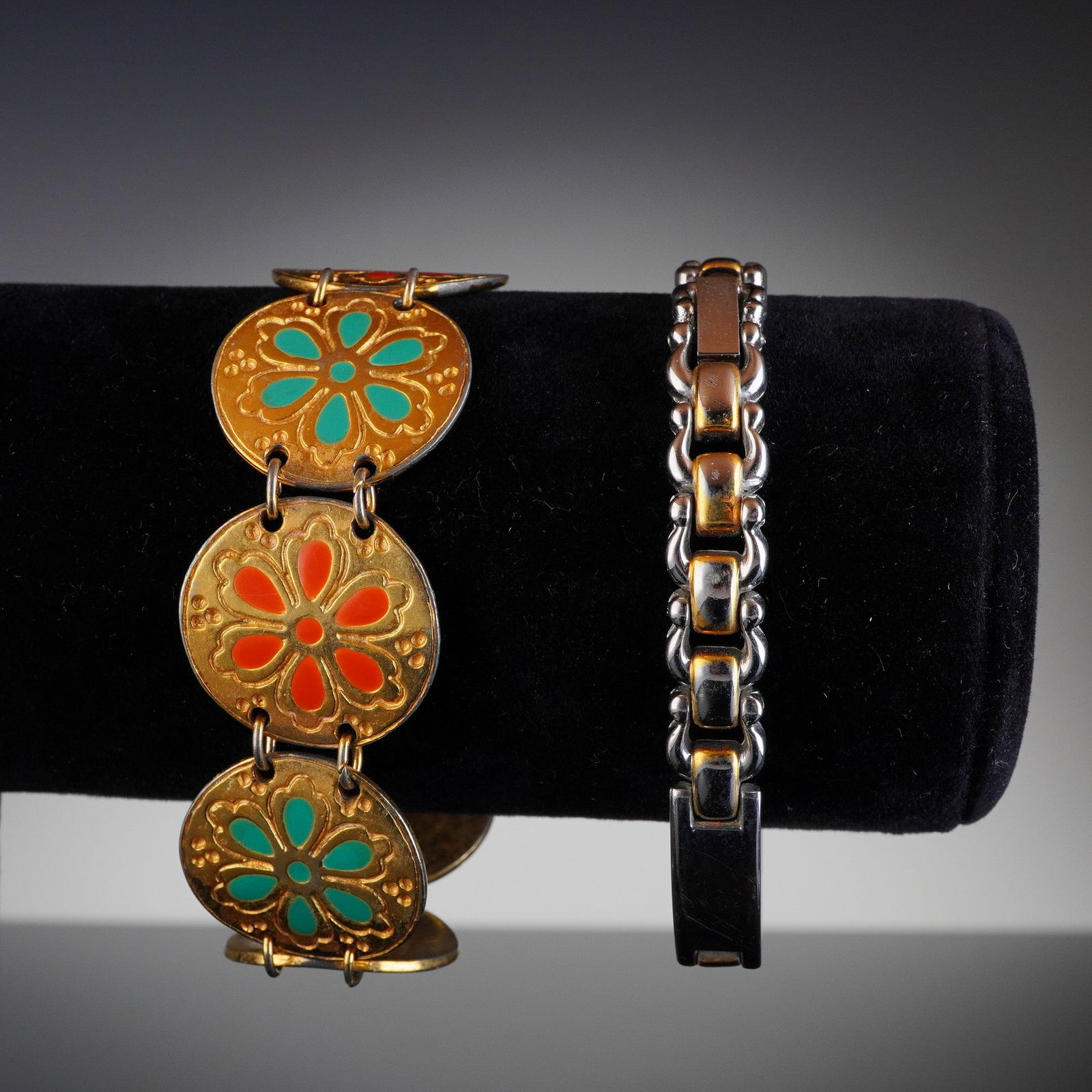 2pc Gold and Silver Tone Bracelets: A group of two gold and silver tone bracelets. The first item is a wide link bracelet constructed of gold-toned base metal discs connected by links. Each disk is decorated with colorful enamel, featur
