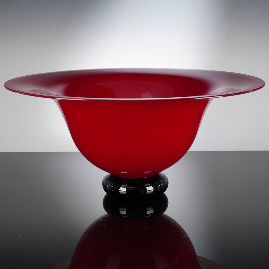 Donald Carlson Studio Art Glass Red Centerpiece Footed Bowl, Signed: This is a single piece of Donald Carlson Studio Art Glass, identified as a centerpiece bowl. The body features a wide, shallow, flared rim and a funnel-shaped profile, executed in vibrant opaque ruby