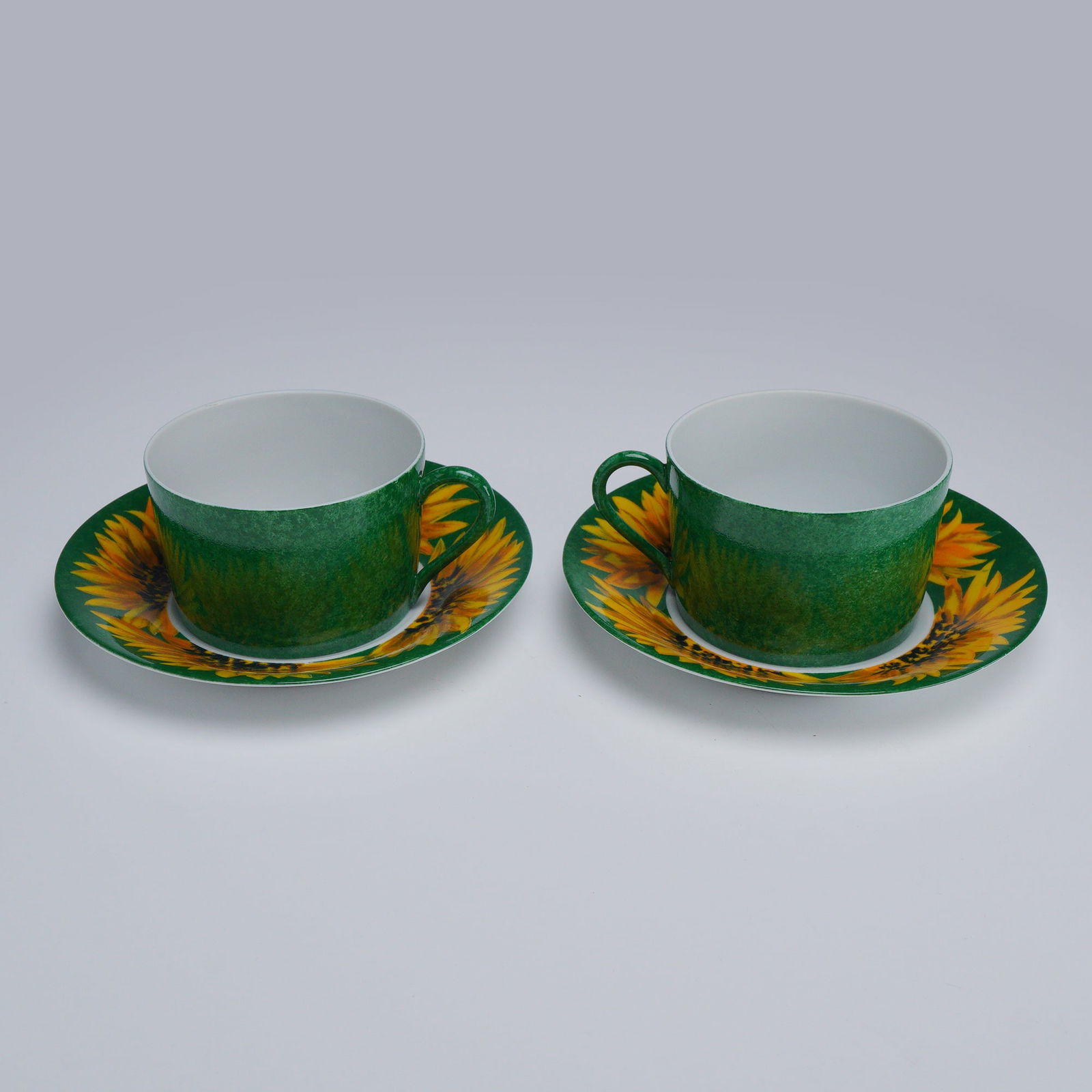 4pc Laure Japy, Made in Limoges for Barney's New York, Teacups & Saucers: Features two sets of Laure Japy teacups with matching saucers, decorated in a vibrant sunflower motif against a Tournesol green background on the saucers. The cups are finished in a Tournesol green.