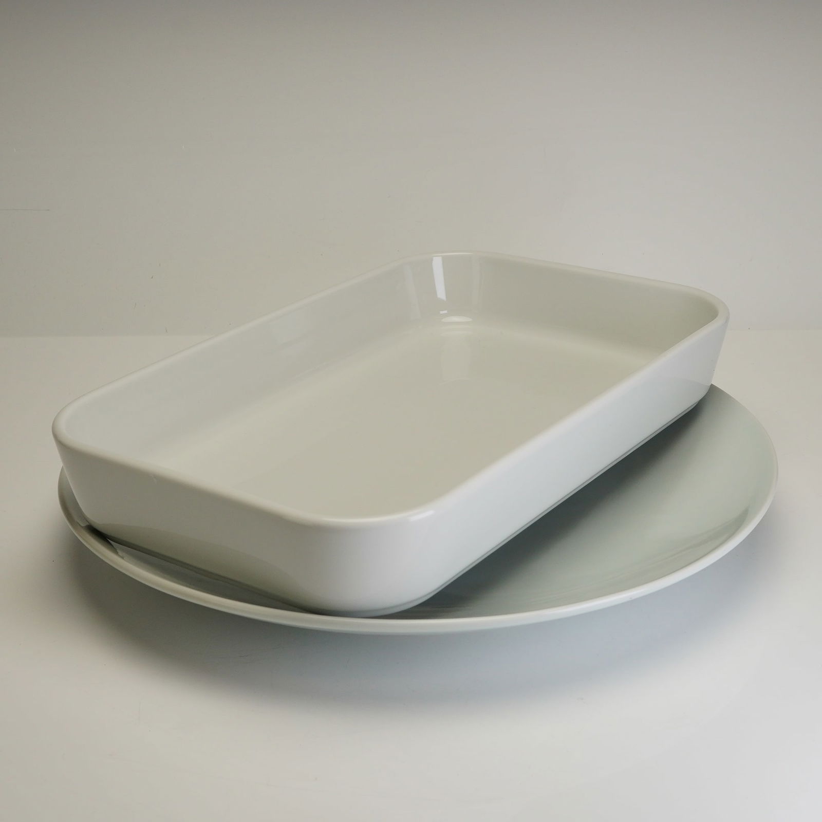 2pc Rosenthal Whiteware Porcelain Serving Dish and Platter: This lot consists of two white porcelain serving dishes featuring a minimalist modern style with a glossy finish. The collection includes one rectangular Rosenthal dish, designed with deep sides suita