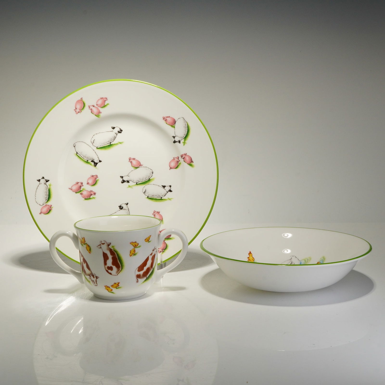 Tiffany & Co. 3 Piece Child's Dinnerware Set, Tiffany Farm: The set consists of a plate, a bowl, and a double-handled mug. Each piece is constructed from fine bone china with a white glazed body and a vibrant green rim. The decoration features illustrations