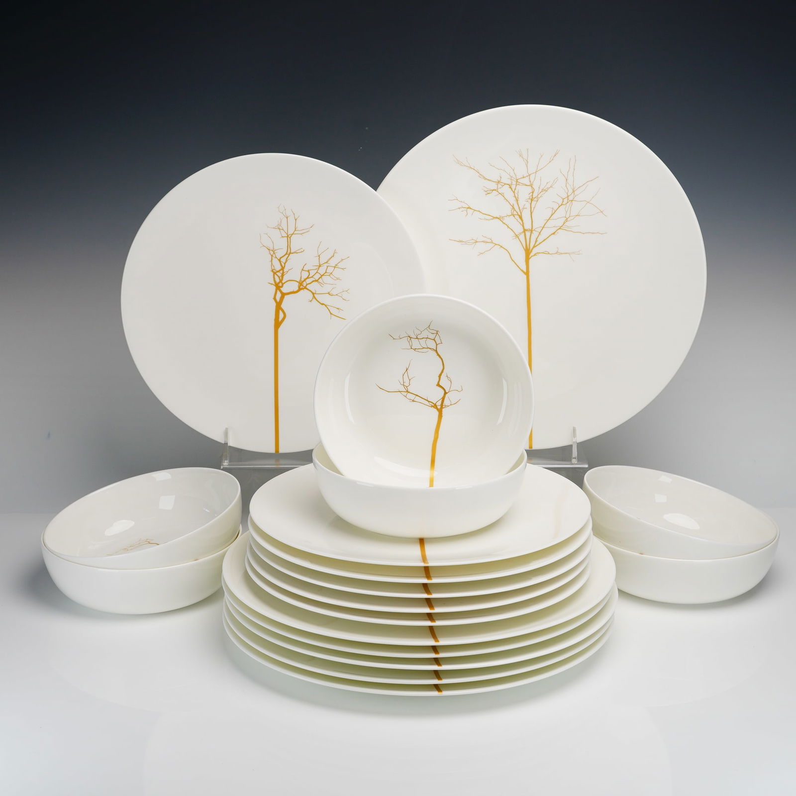 18pc Dibbern Germany Porcelain Dinnerware, Golden Forest: Contemporary white porcelain dinnerware manufactured by Dibbern, Germany, in the Golden Forest pattern. The set comprises six 10" dinner plates, six 7" bowls, and six 12" Chargers. Each piece is