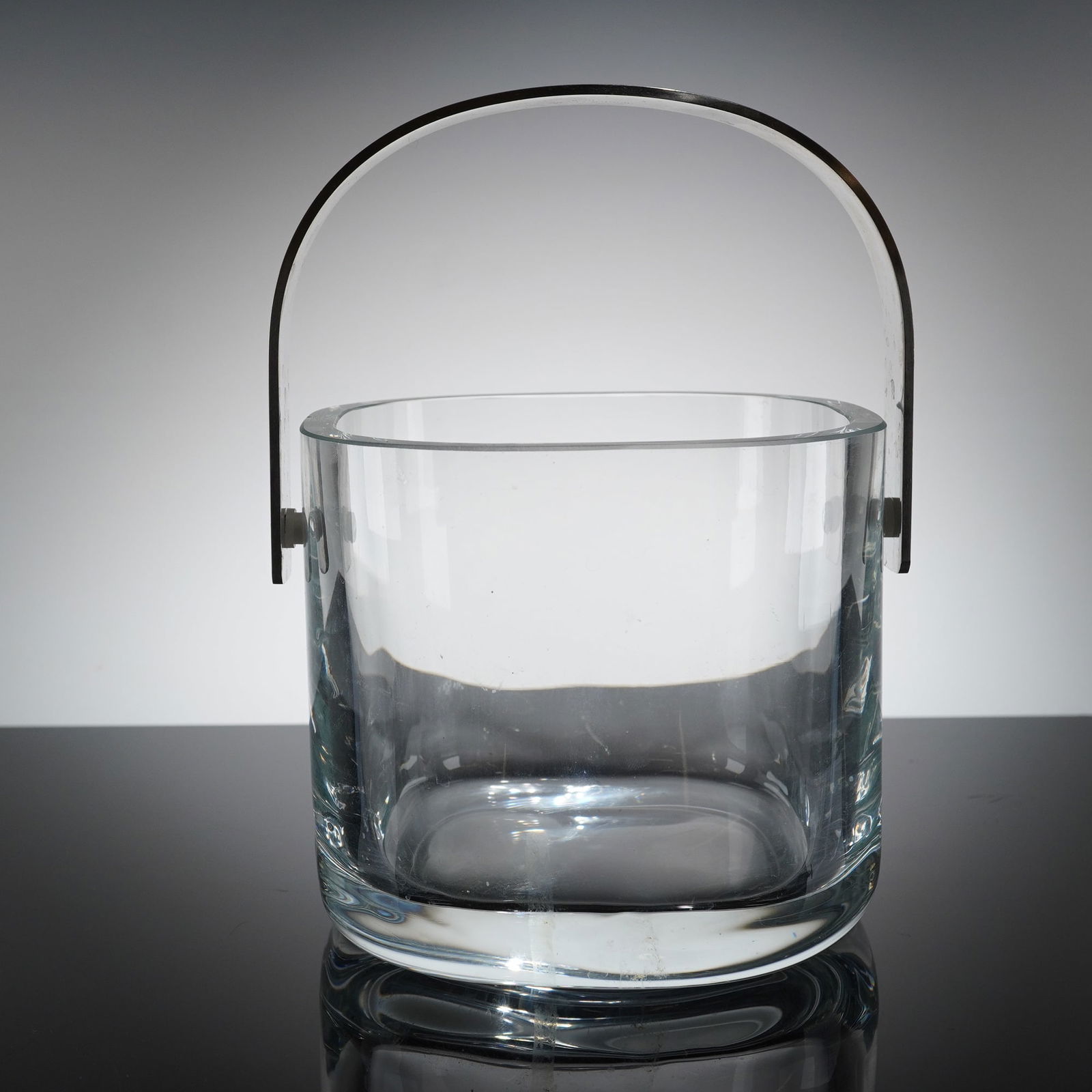 Orrefors Mid-Century Modern Glass and Stainless Steel Ice Bucket: A single Mid-Century Modern ice bucket manufactured by Orrefors, Sweden. The item features a cylindrical body constructed from clear glass with a thick base. It is fited with a wide, polished