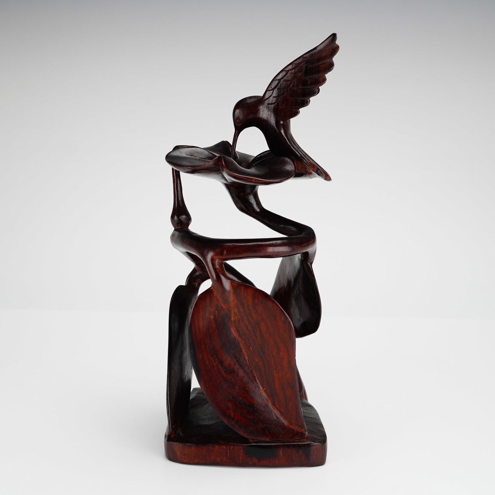 Signed Panamanian Hand-Carved Cocobolo Wood Hummingbird Figurine: An intricately hand-carved cocobolo wood hummingbird figurine from Panama. The piece is crafted from a dense, dark-grained wood with a polished, deep reddish-brown finish. The sculpture depicts a humm