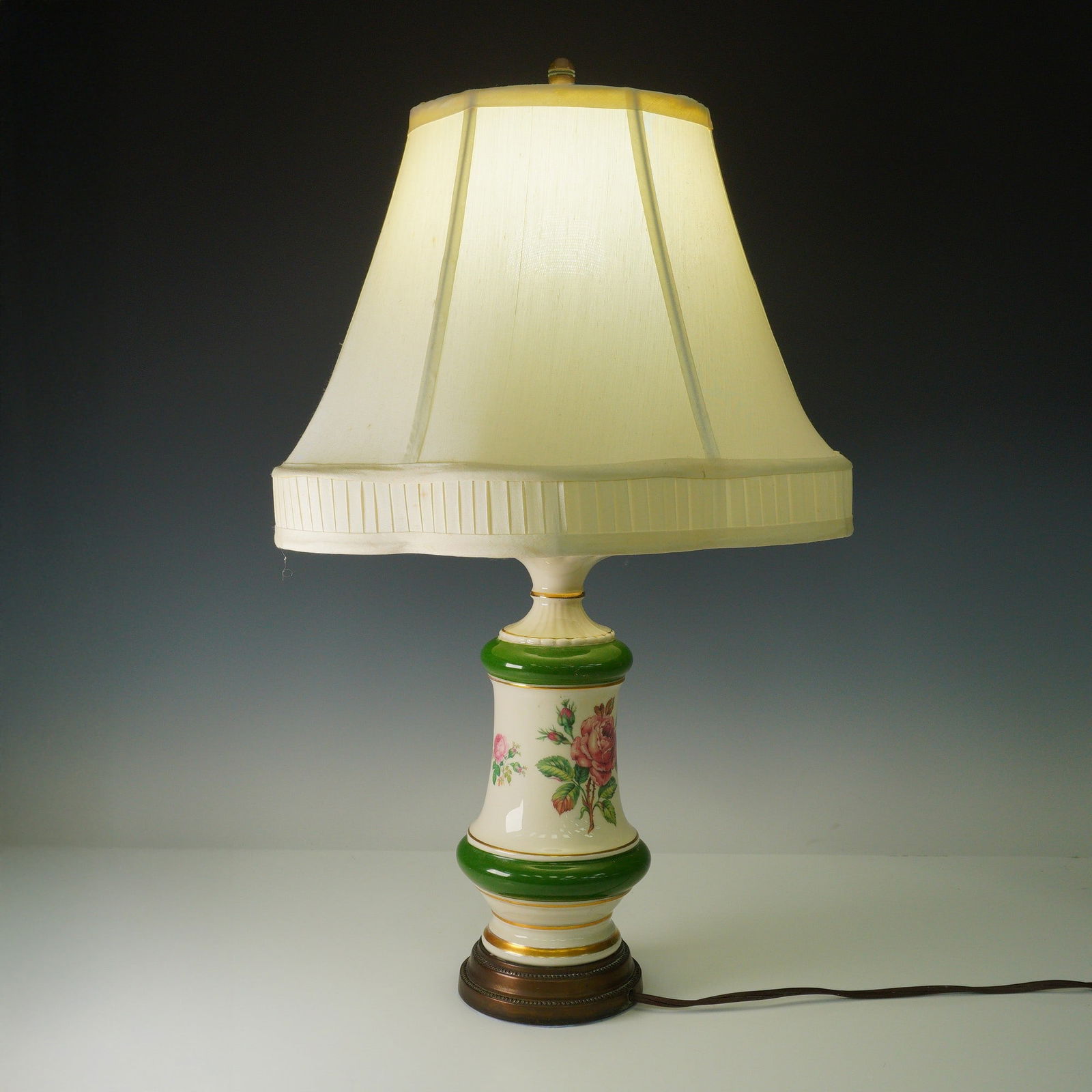 Porcelain Table Lamp with Floral Decoration: Vintage electric table lamp featuring a porcelain body with hand-applied floral transfers in red and pink, accented by vivid green bands and gilt highlights. Single socket with lightbulb included. Lam