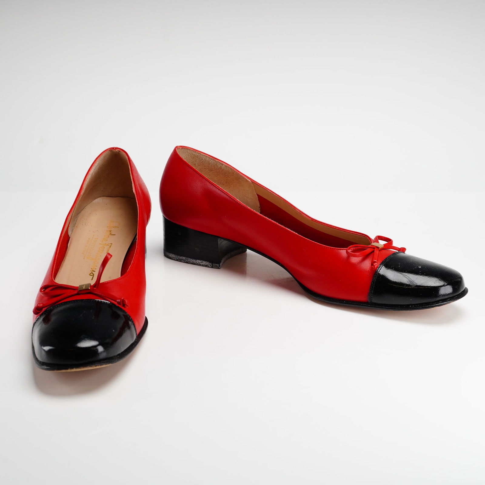 Pair of Salvatore Ferragamo Boutique Two-Tone Leather Pumps: A pair of Salvatore Ferragamo Boutique pumps featuring a two-tone design with red leather uppers and contrasting black patent leather cap-toes. The shoes are constructed with a low black block heel