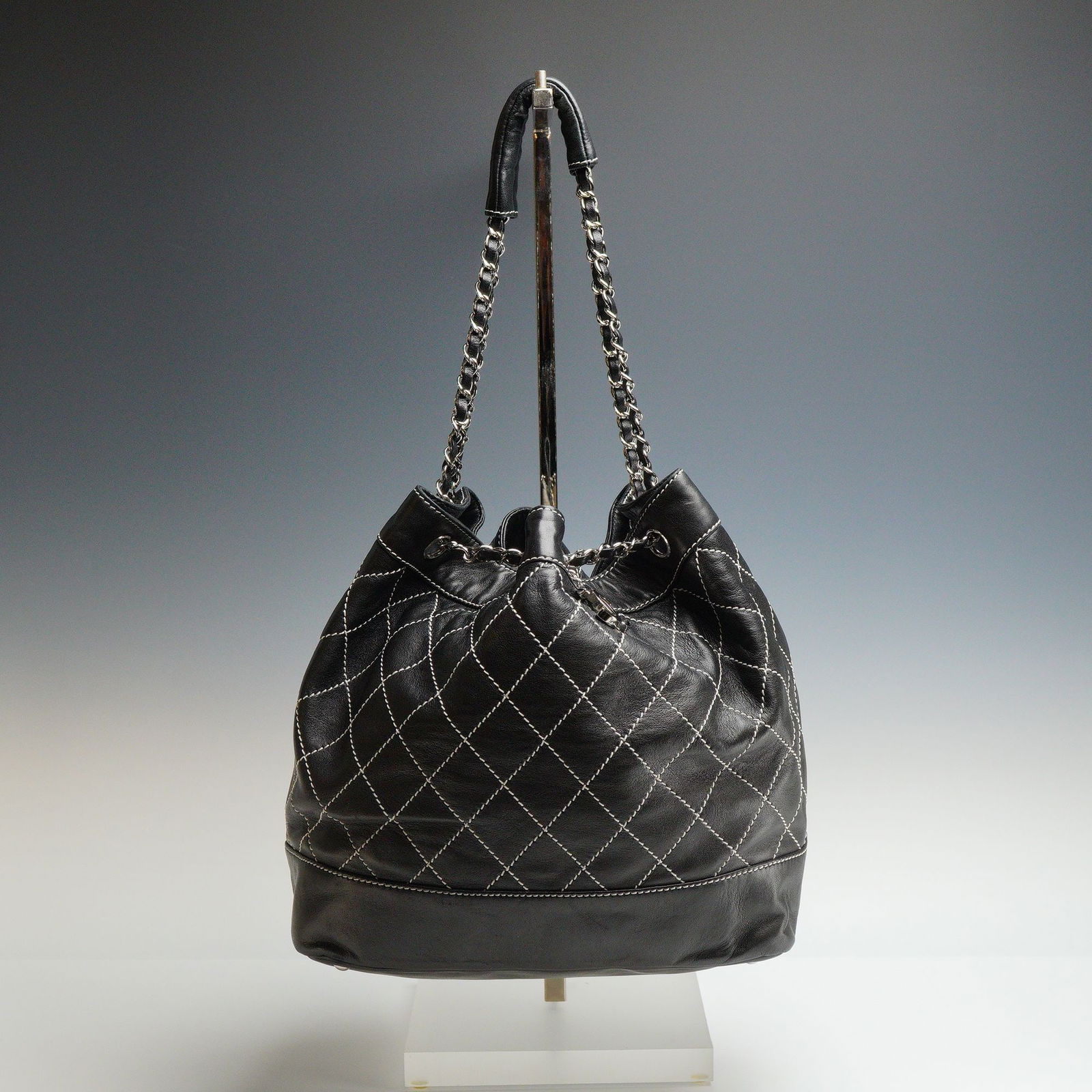 Chanel Surpique Drawstring Black Bucket Bag: Authentic Chanel Surpique Drawstring Bucket Bag in classic black leather. This refined bucket silhouette showcases Chanel's signature craftsmanship, with elegant stitched detailing and a structured ye