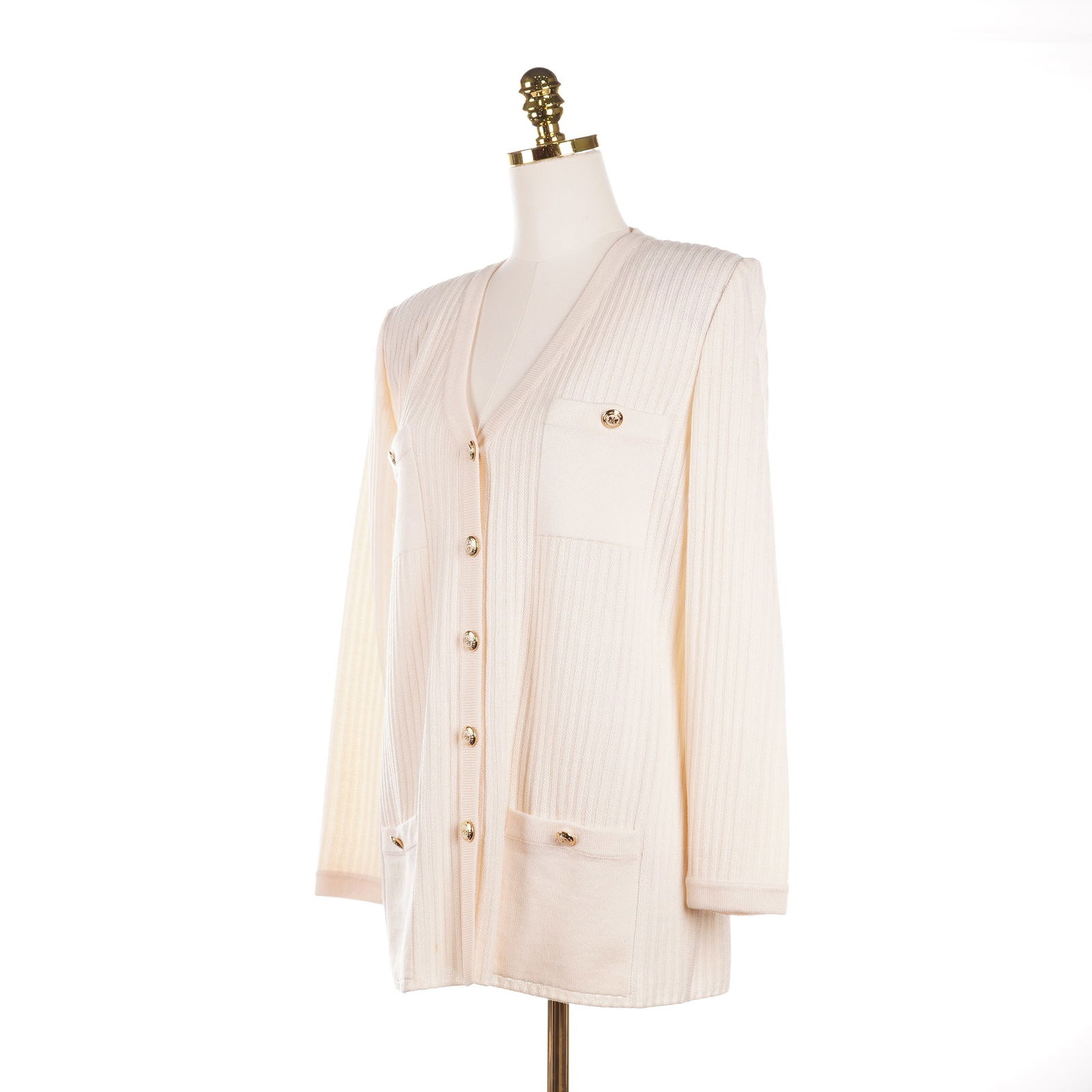 St. John Basics Ribbed Knit Button Front Jacket with Pockets: A St. John Basics cream-colored ribbed knit longline cardigan jacket constructed with a vertical ribbed knit texture and features a V-neckline. The front closure consists of five gold-tone buttons emb