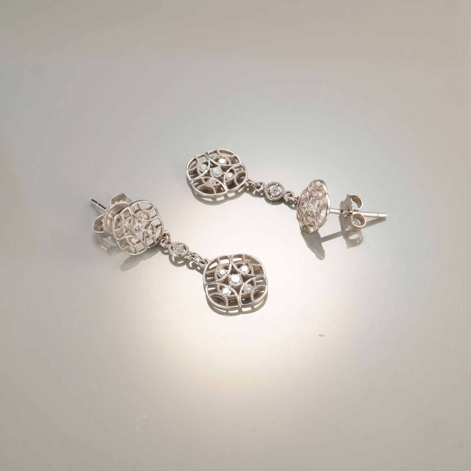 Pair of 18K White Gold 0.37ctw Diamond Dangle Earrings: A graceful pair of 18K white gold dangle earrings showcasing an intricate openwork design set with approximately 0.37 carats total weight of round brilliant-cut white diamonds. Each earring features a