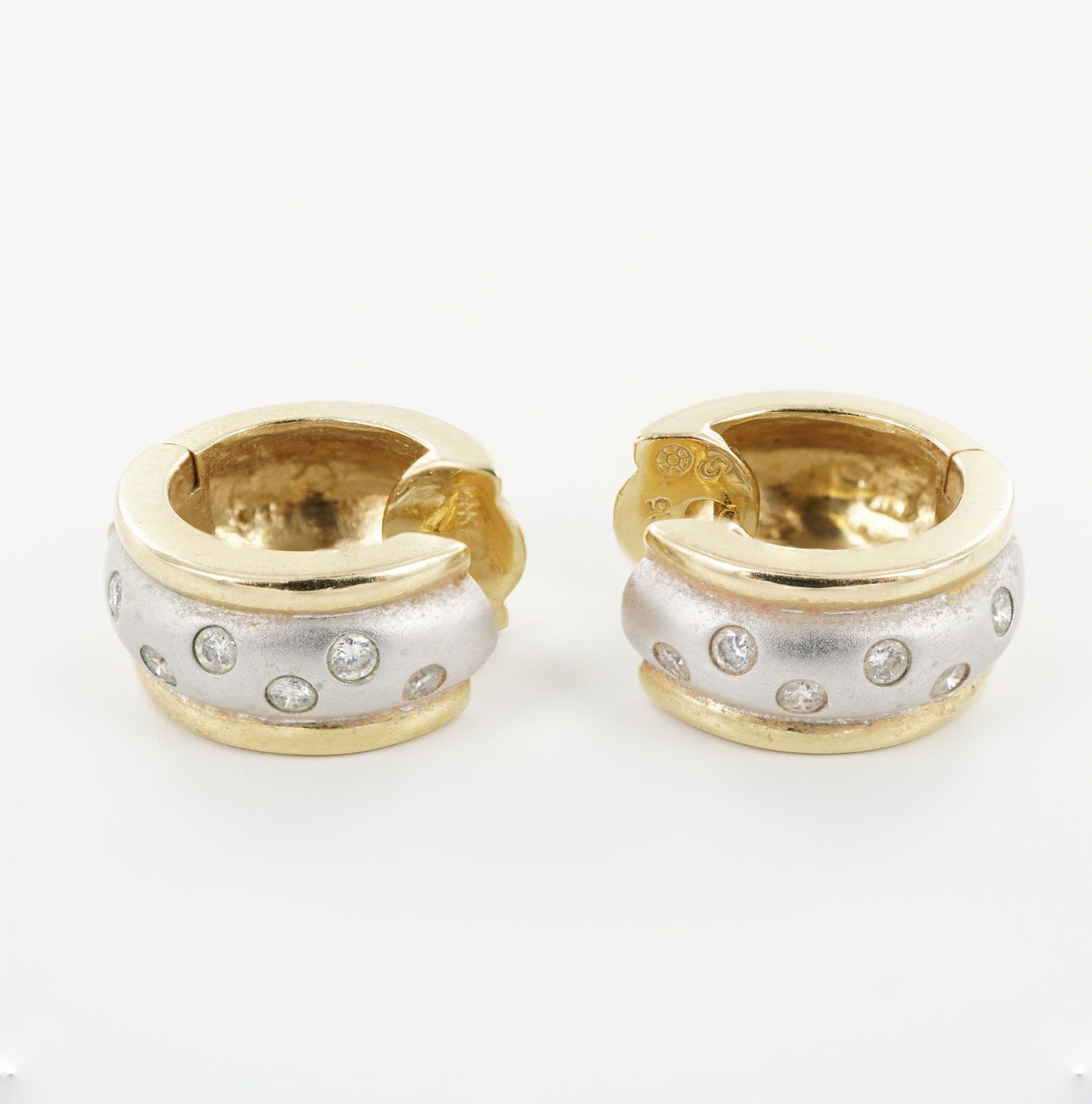 14K Gold and Diamond Two-Tone Hoop Earrings: This pair of 14K two-tone gold hoop earrings features a satin-finished white gold center band framed by polished yellow gold borders. Each earring is set with six round diamonds, adding a refined touc