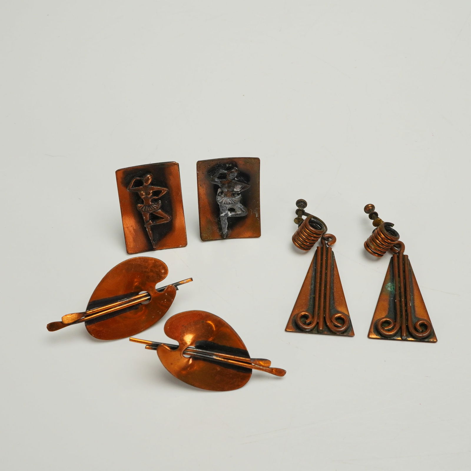 3 Pairs of Copper Tone Clip On Earrings: A collection of six individual pieces (three pairs) of Mid-Century Modern copper tone costume jewelry. The lot includes three distinct pairs of earrings. The first pair consists of square clip-on earr