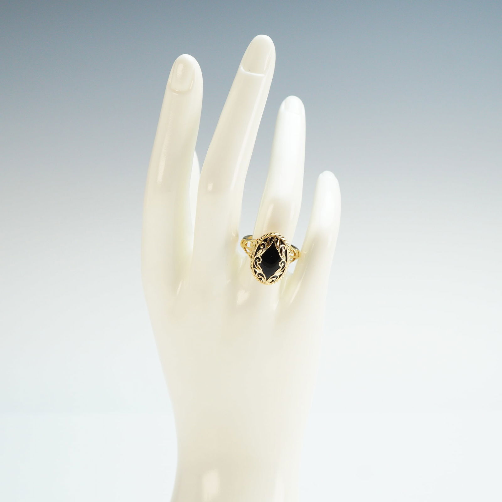 14K Gold Oval Onyx Scrollwork Ring: A 14K yellow gold ring featuring an oval onyx. The stone is encased in a decorative scrollwork motif, which continues along the open gallery. The band is marked 14K. Dimensions: Ring size: 7.25 Weight