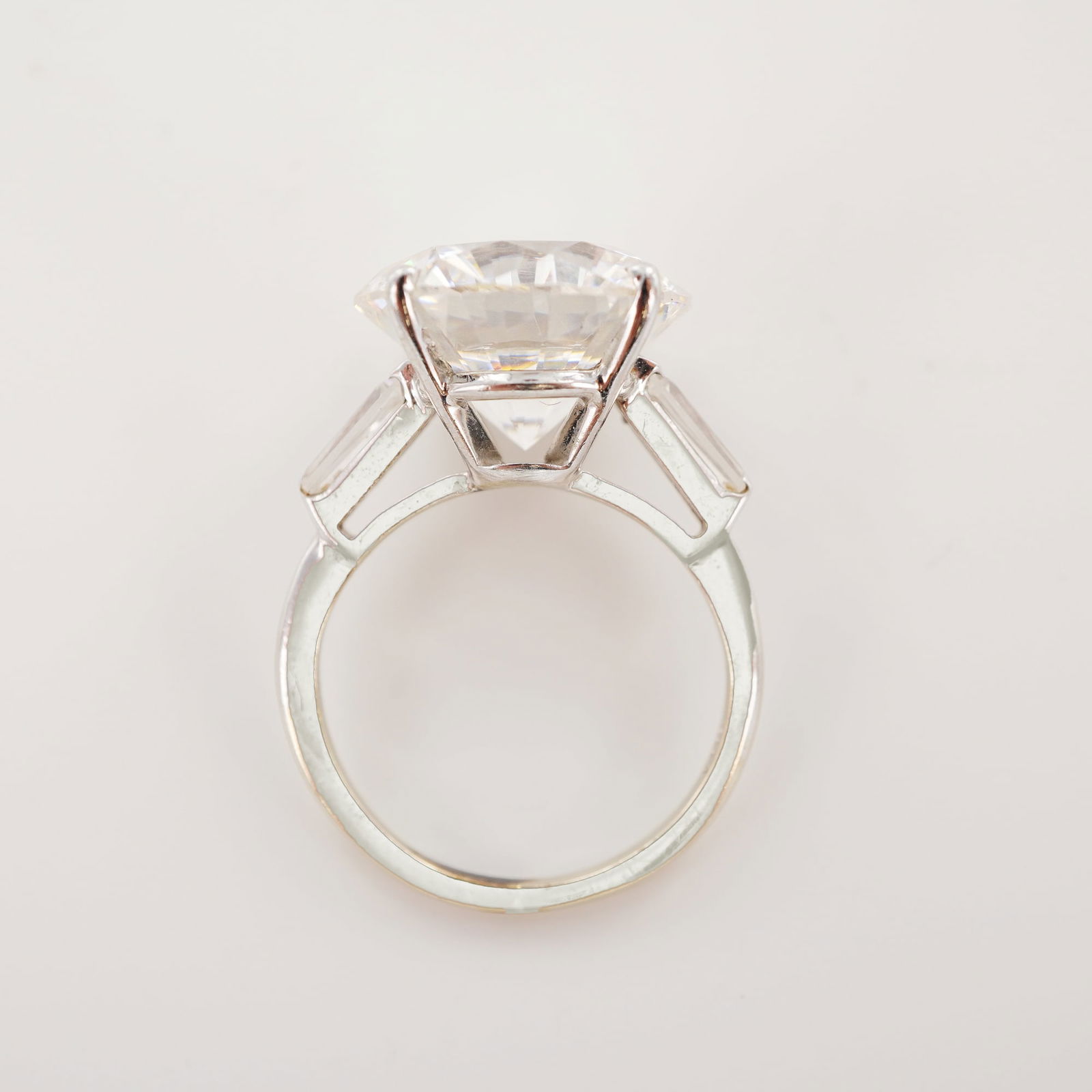 14K White Gold Round and Baguette Cut Stone Ring: Marked 14K white gold ring featuring a round brilliant-cut center stone flanked by tapered baguette side stones in a classic three-stone prong setting with open gallery. Weight: 6.8 g. Dimensions: Rin