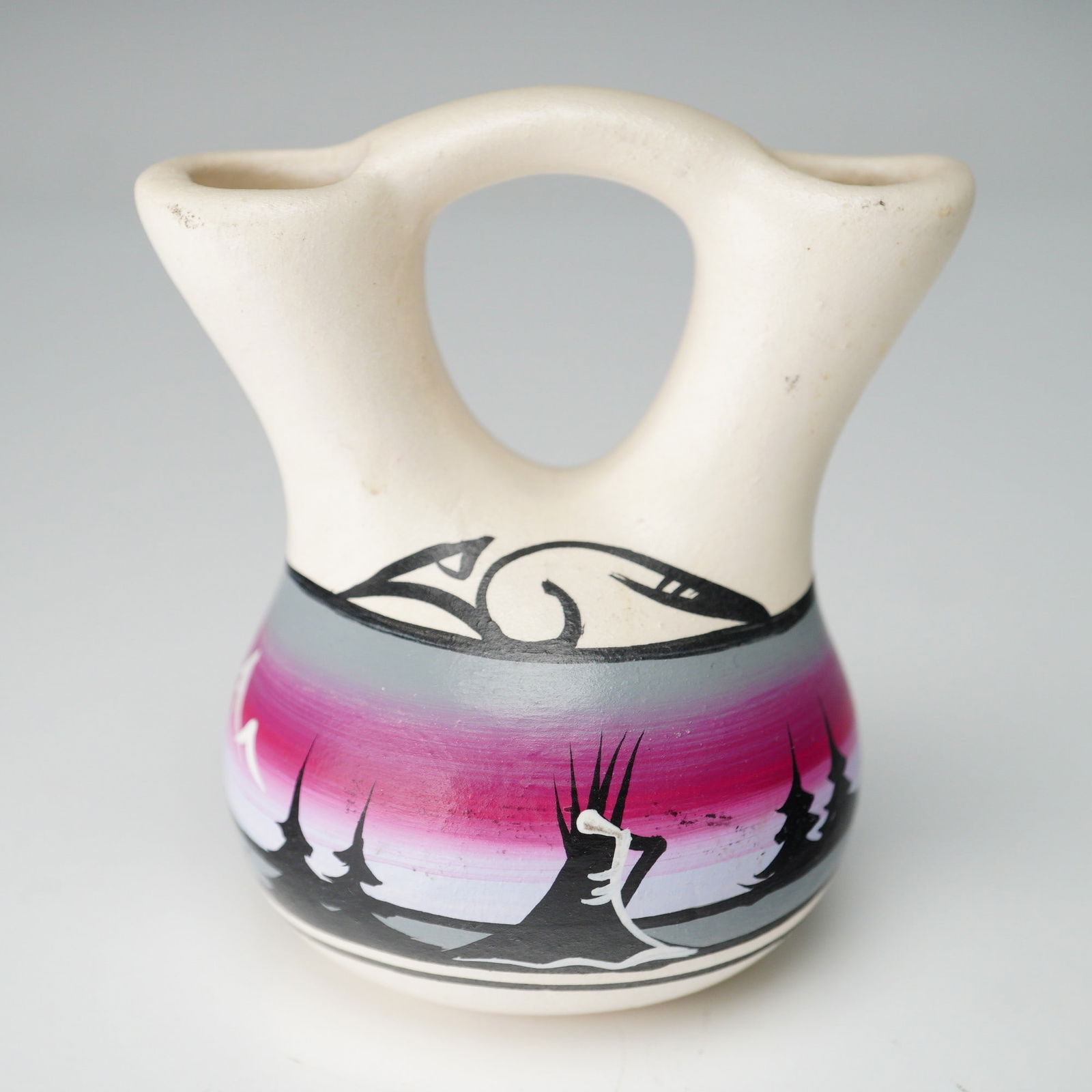 Hand-Painted Native American Wedding Vase: Small hand-painted pottery wedding vase featuring a double-spout form with central bridge handle, painted in gradient hues of pink, purple, and gray. The body is decorated with bold black silhouettes