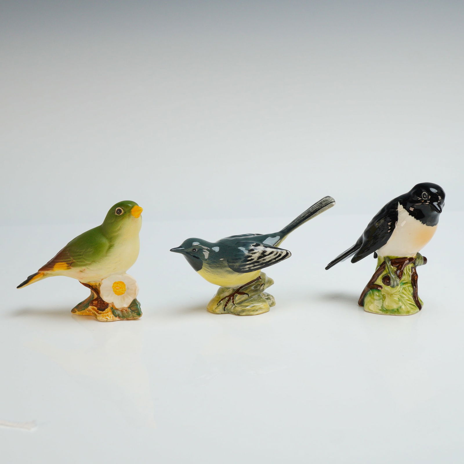 3pc Beswick Porcelain Bird Figurines, Stonechat, Greenfinch, & Grey Wagtail: This collection consists of three Beswick porcelain bird figurines, specifically a Stonechat 2274, a Greenfinch 2105, and a Grey Wagtail 1041. Each piece is modeled with naturalistic coloring and