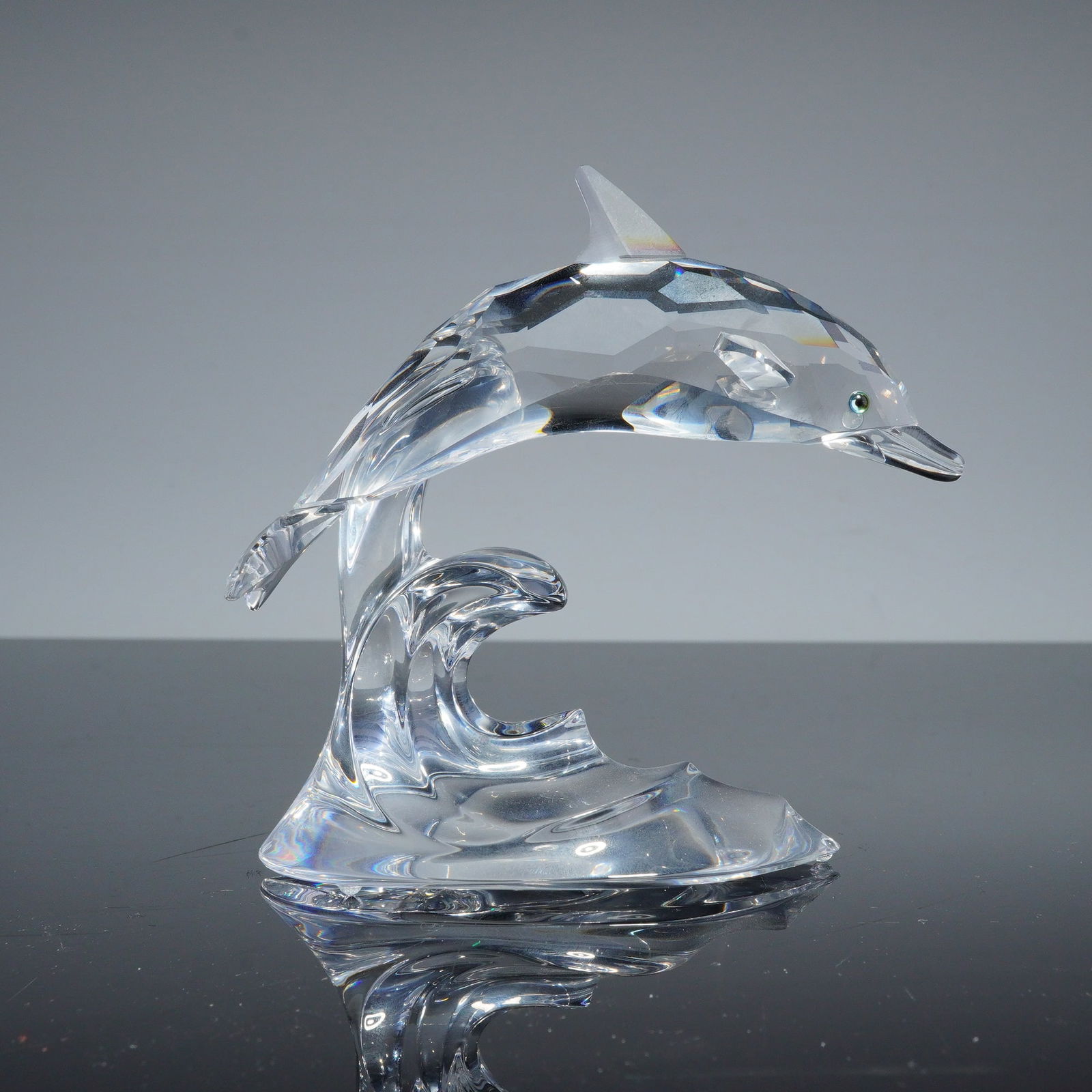 Swarovski Crystal Figurine, Dolphin on a Wave: Swarovski Crystal Dolphin on a Wave, model number 190365, from the Sea Animal series. This figurine is composed of faceted lead crystal and depicts a dolphin leaping over a cresting wave. The dolphin