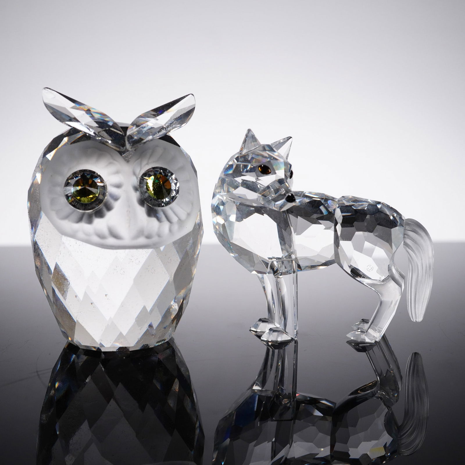 2pc Swarovski Crystal Figurines, Owl and Wolf: Elegant two-piece Swarovski Silver Crystal animal figurine set, comprising a faceted owl and a standing wolf. The owl features a stylized geometric body with finely detailed facial sculpting and