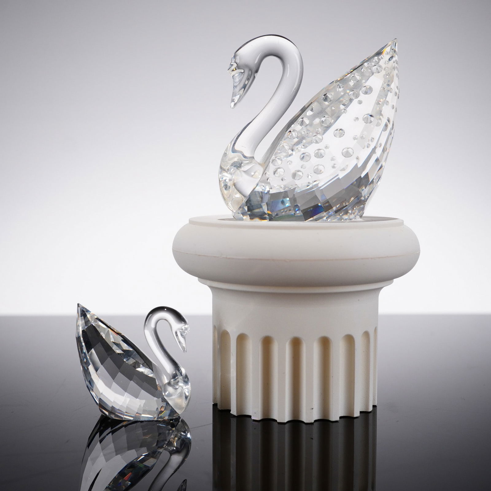 2pc Swarovski Crystal Swan Figurines: Charming two-piece Swarovski Silver Crystal swan figurine set, including a larger decorative swan and a smaller companion swan. Both are expertly crafted in clear, precision-cut crystal, showcasing