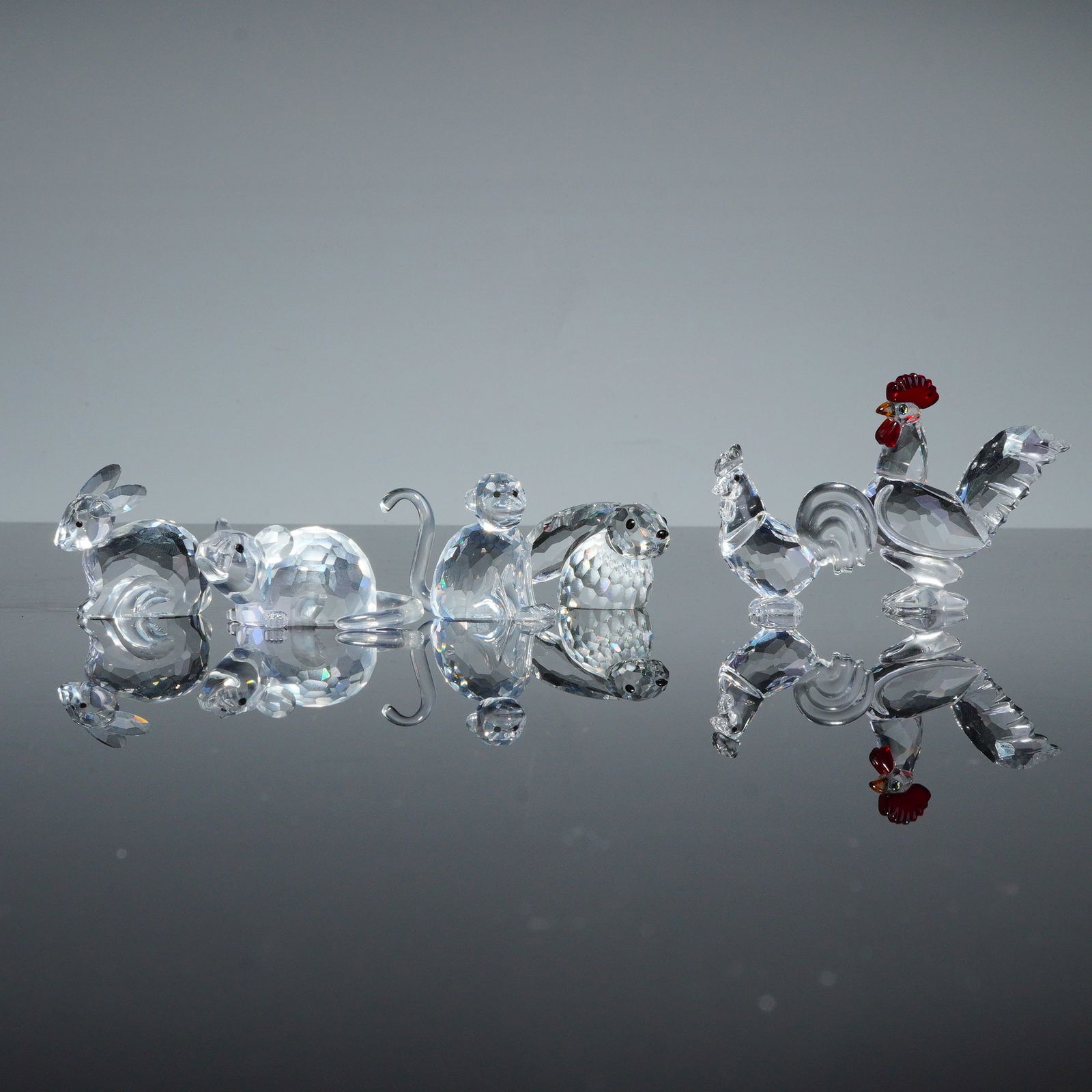 6pc Swarovski Crystal Animal Figurines: A collection of Swarovski faceted crystal animal figurines, including representations of a rabbits, rat, monkey, and cockerels. Each figure is crafted from clear precision-cut crystal designed for
