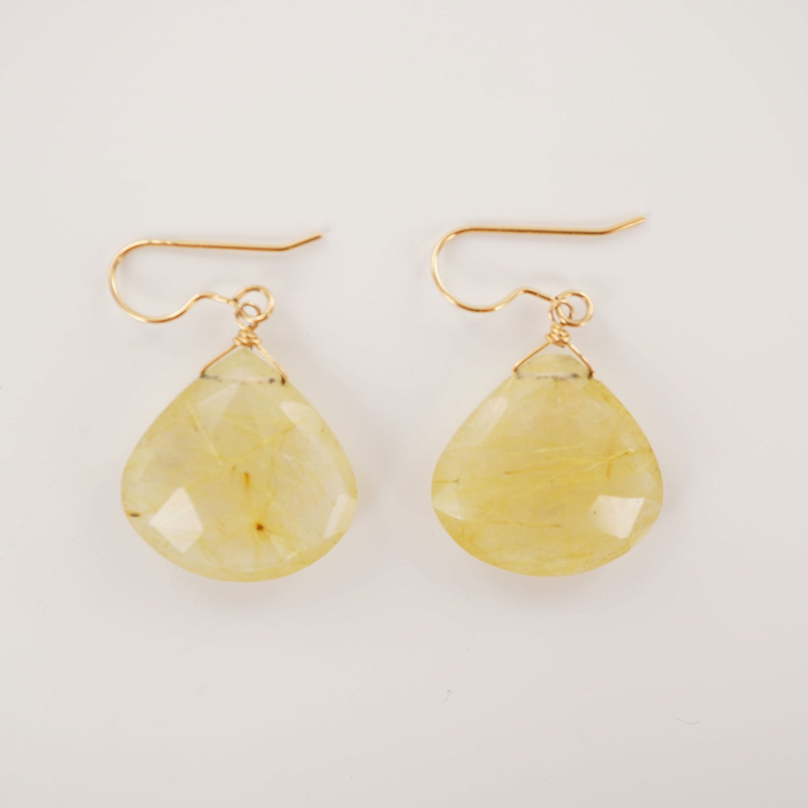 14K Gold Filled Rutilated Quartz Drop Earrings: Drop earrings featuring faceted teardrop-shaped rutilated quartz stones suspended from 14K gold filled hooks. Each stone displays visible golden needle-like inclusions characteristic of rutilated quar