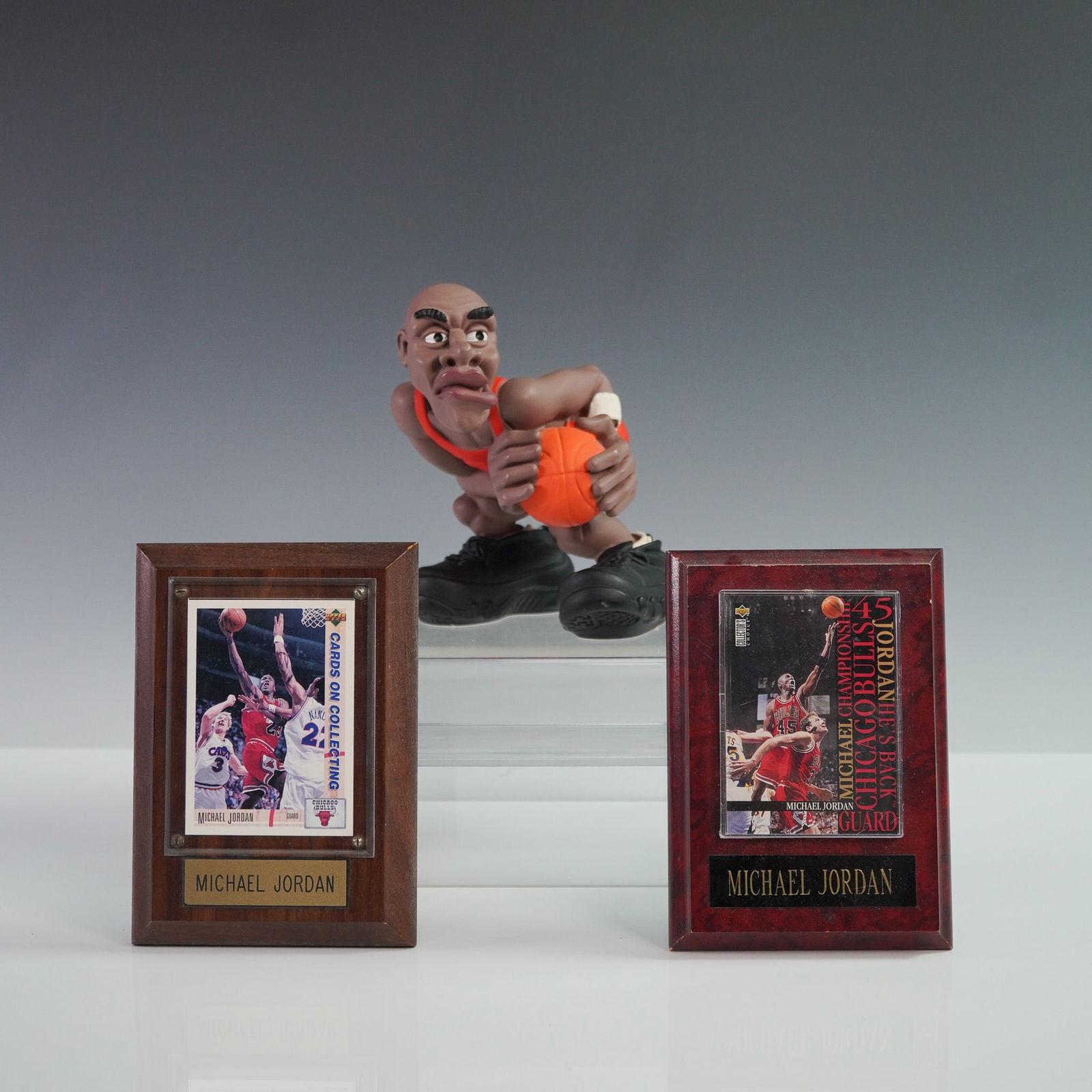 3pc Michael Jordan Lot, Plaque Cards & Basketball Figurine: Three-piece Michael Jordan collectible lot featuring two trading cards mounted on individual plaques and a stylized figurine of Jordan in action. The cards are preserved under clear acrylic on wooden