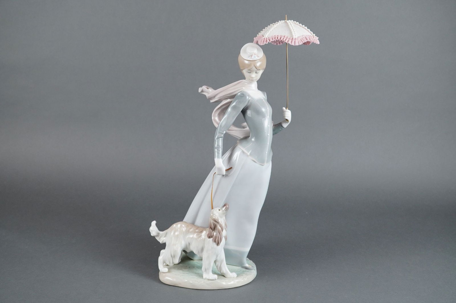 Lladro Glazed Porcelain Sculpture Lady with Shawl 4914: This is a Lladro glazed porcelain sculpture, model number 4914, titled "Lady with Shawl" (also known as "A Walk with the Dog"). The figurine depicts a lady in period attire, featuring a pale blue dres