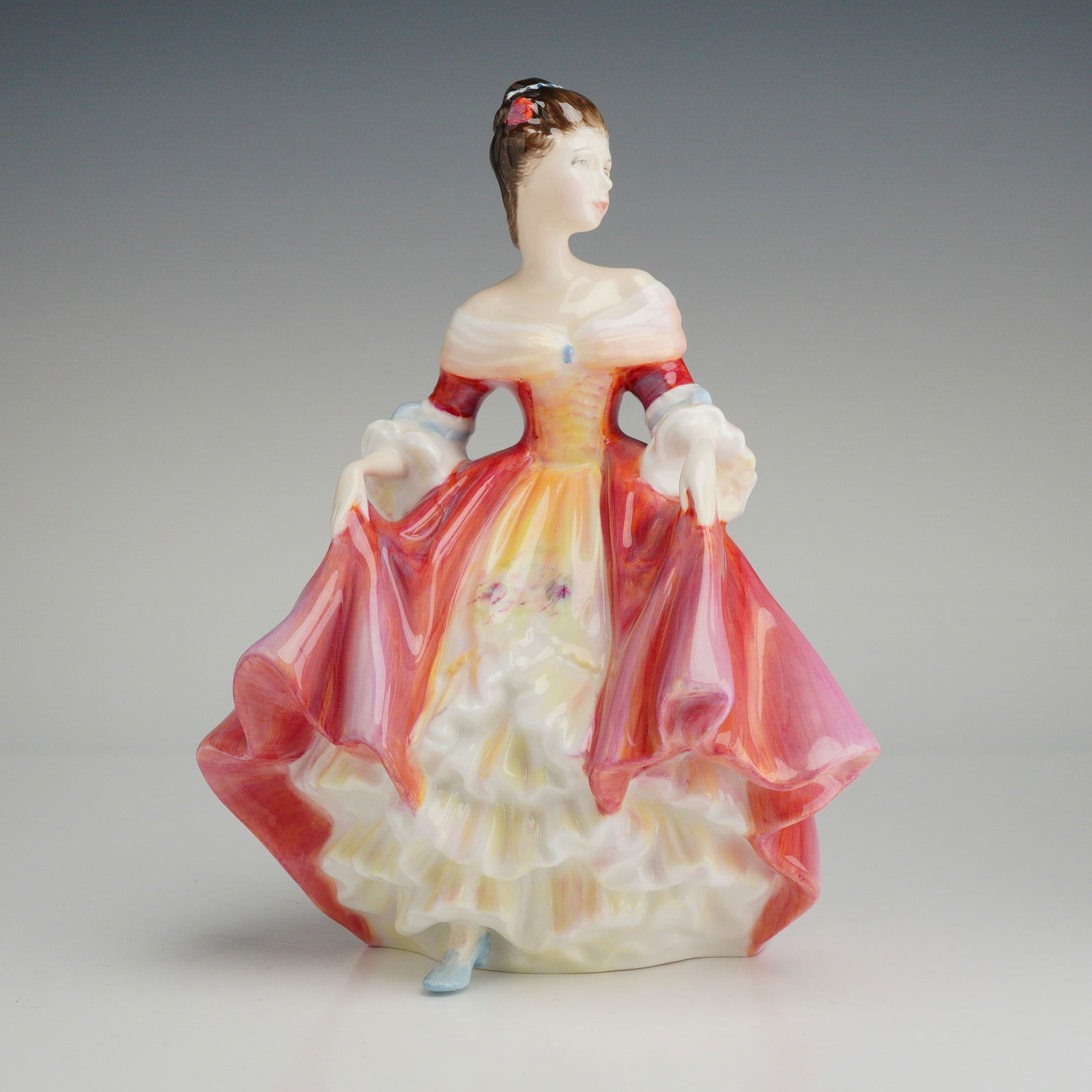 Royal Doulton Figurine, Southern Belle HN2229: A Royal Doulton bone china figurine titled Southern Belle, model number HN 2229, modeled by Peggy Davies. This hand-made and hand-decorated piece depicts a woman in an off-the-shoulder red gown with p