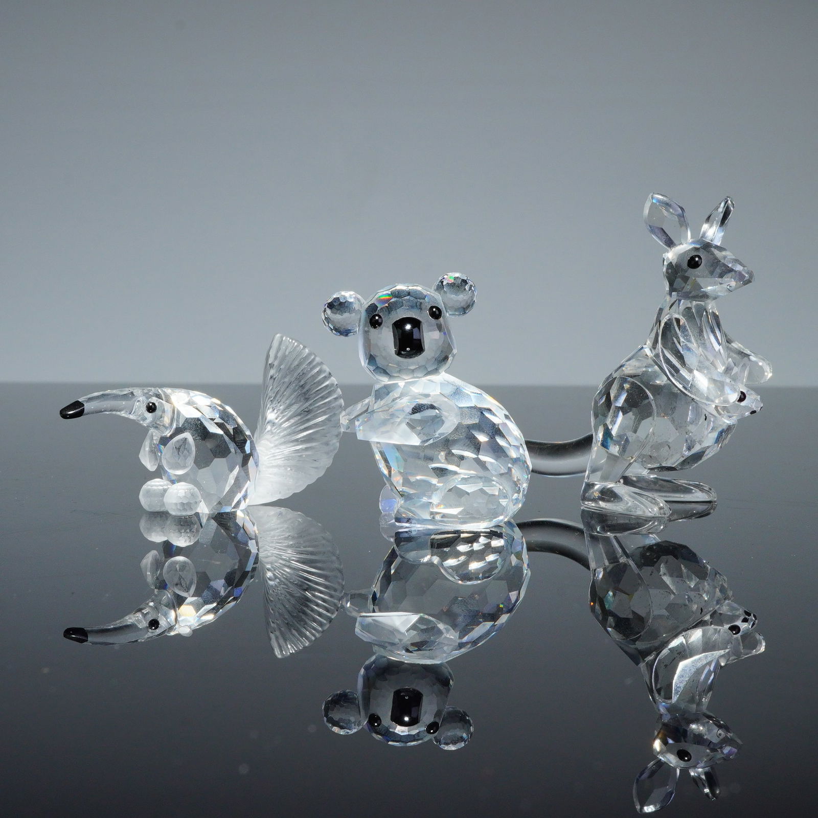 3pc Swarovski Silver Crystal Animal Figurines: A trio of Swarovski faceted lead crystal animal figurines from the Silver Crystal series. The collection includes an anteater featuring a frosted, textured tail, a seated koala with black stone accent