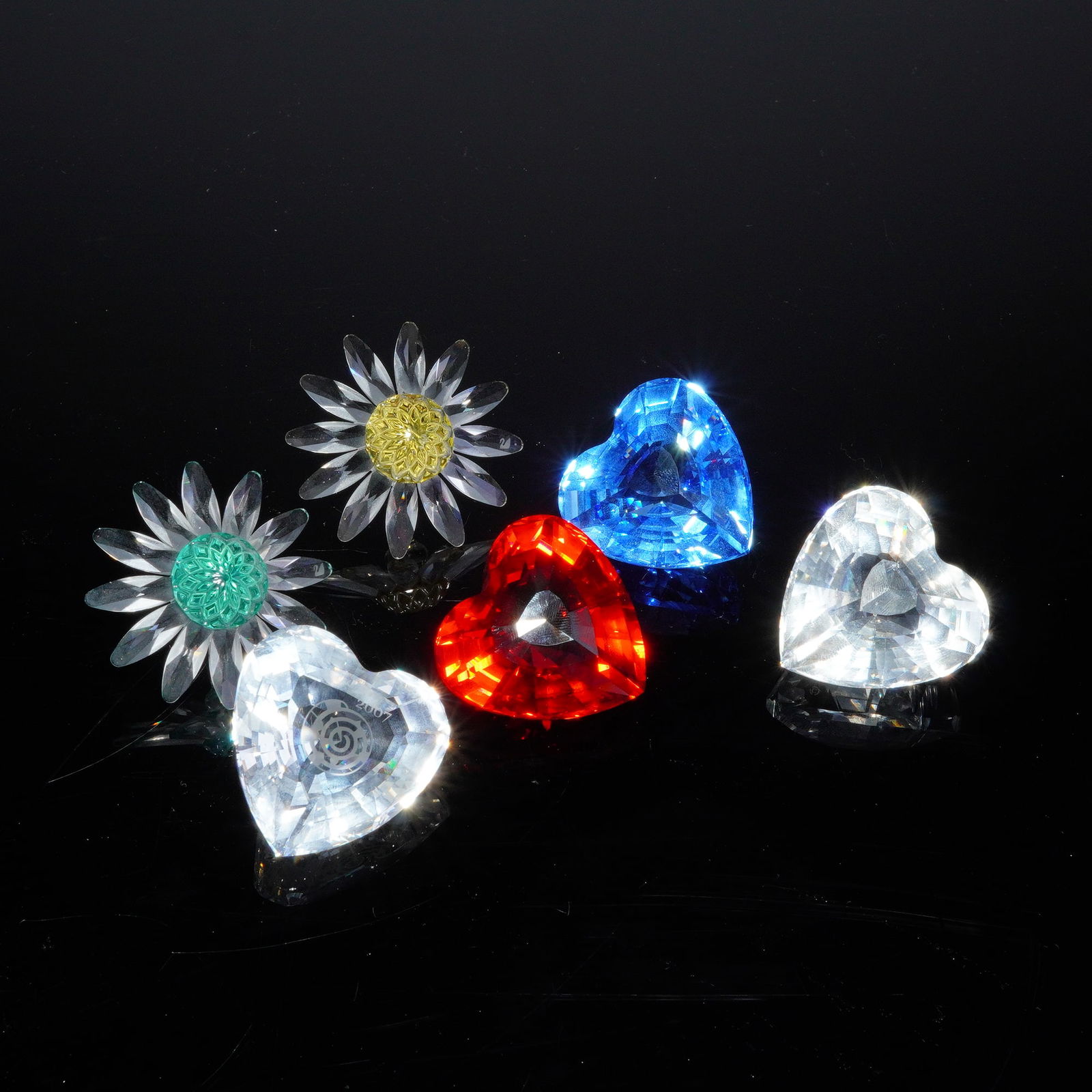 6pc Swarovski Crystal Figurines, Hearts and Flowers: A collection of Swarovski faceted crystal figurines featuring various heart and floral motifs. The group includes heart-shaped crystals in translucent red, translucent blue, and clear finishes. One cl