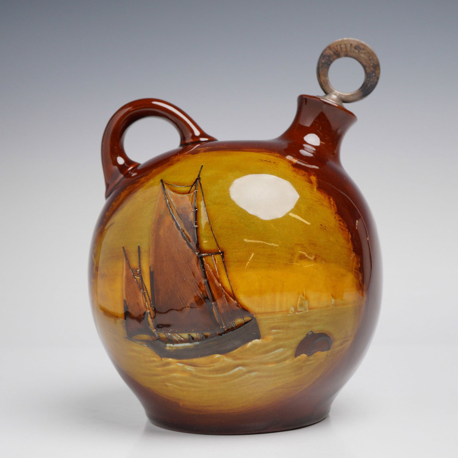 Royal Doulton Kingsware Whisky Flask, Fisherman: A Royal Doulton Kingsware glazed ceramic whisky flask of globular form, featuring a loop handle and an offset spout. The vessel is decorated with slip-trailed and hand-painted scenes. One side depicts
