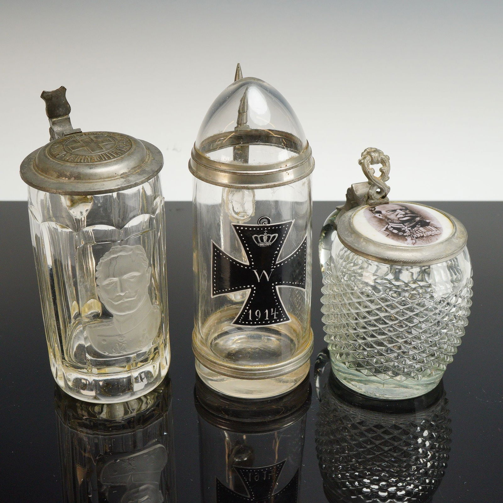 3pc German Commemorative Glass and Metal Steins: This 3pc collection of Imperial German glass and metal steins dates to the early 20th century, specifically the World War I period. The group includes a fluted clear glass vessel featuring an etched m