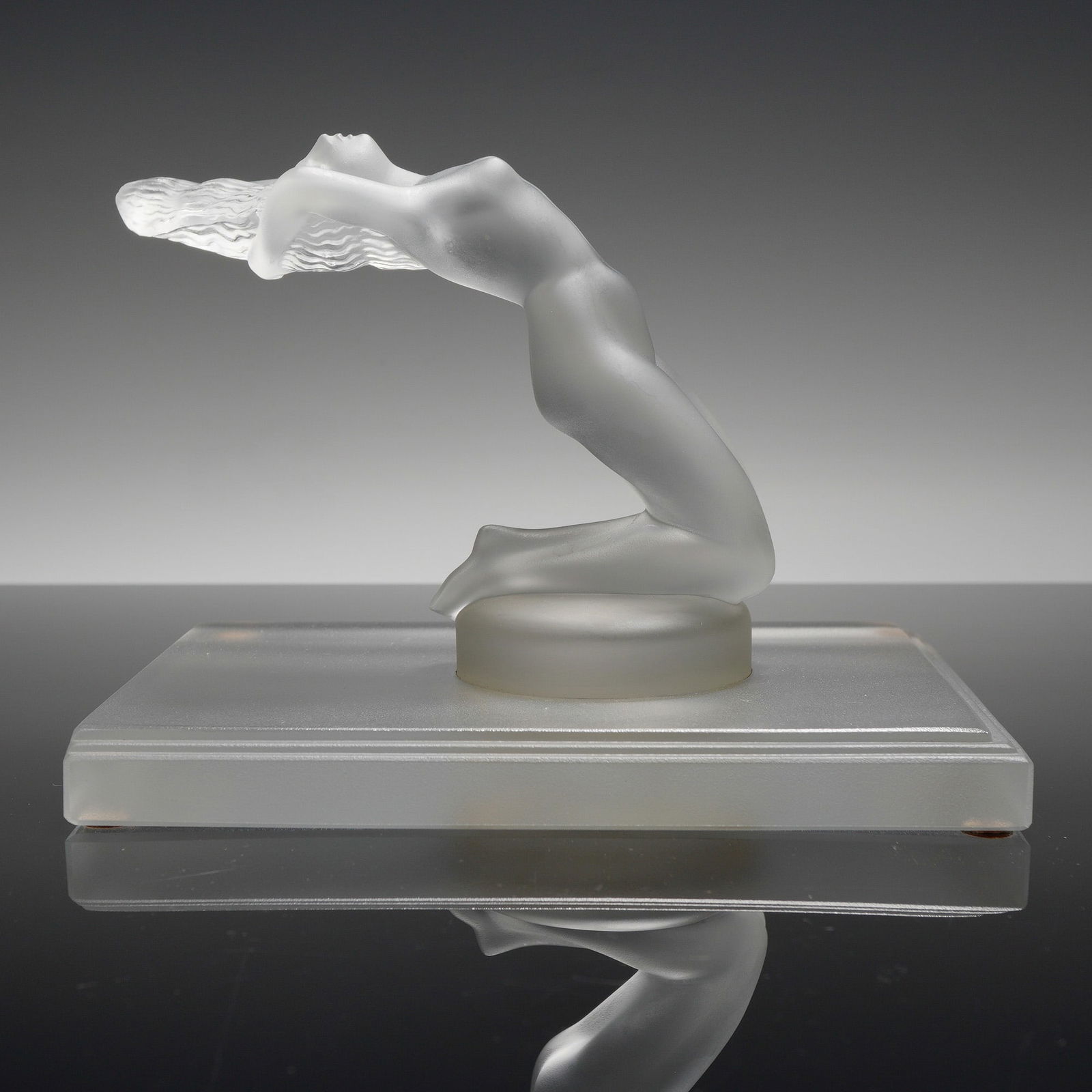 Lalique Frosted Glass Car Mascot, Chrysis: A Lalique design originally created by Rene Lalique in 1931. The piece depicts a kneeling nude female figure in a dynamic arching pose with hair flowing behind her. The sculpture is executed in satin-