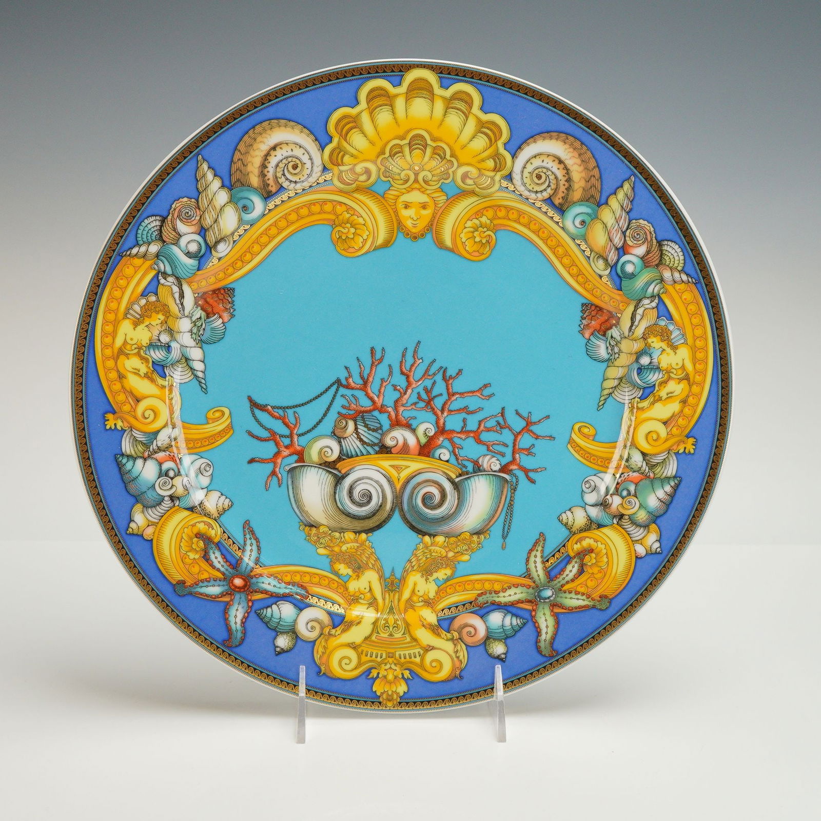 Rosenthal Versace Porcelain Charger, Les Tresors de la Mer: Porcelain charger features in a blue ground hue with seashell, coral and goddess motifs. Decorated with acanthus leaves along the rim. Rosenthal Versace "Le Tresors De La Mer" backstamp on base. Dimen