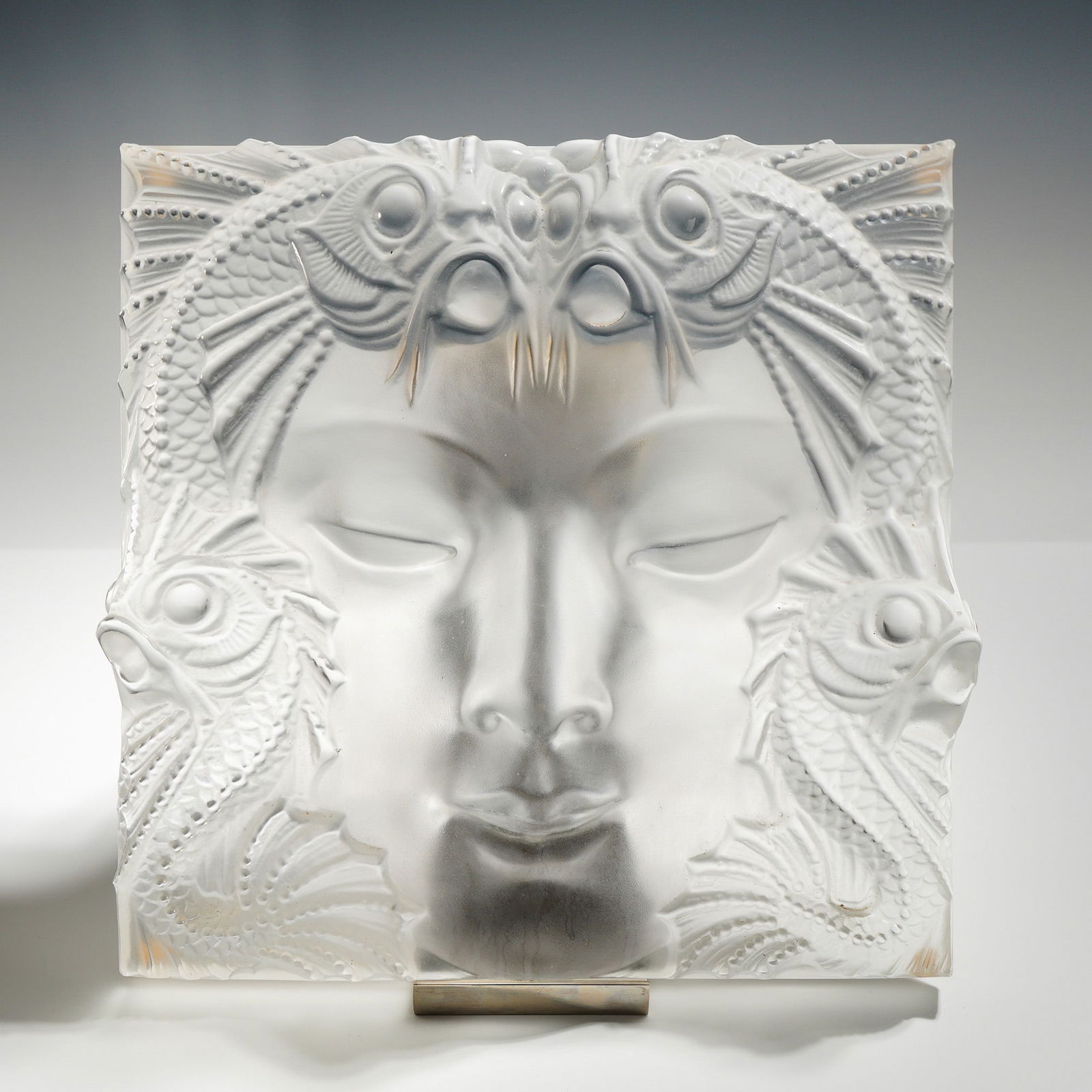 Lalique Crystal Panel, Masque de Femme with Stand: Rene Lalique's mastery of Art Deco design, this Lalique Crystal "Masque de Femme" Panel presents the iconic female face surrounded by aquatic motifsmermaids, fish, and flowing wavesexpertly sculpted i