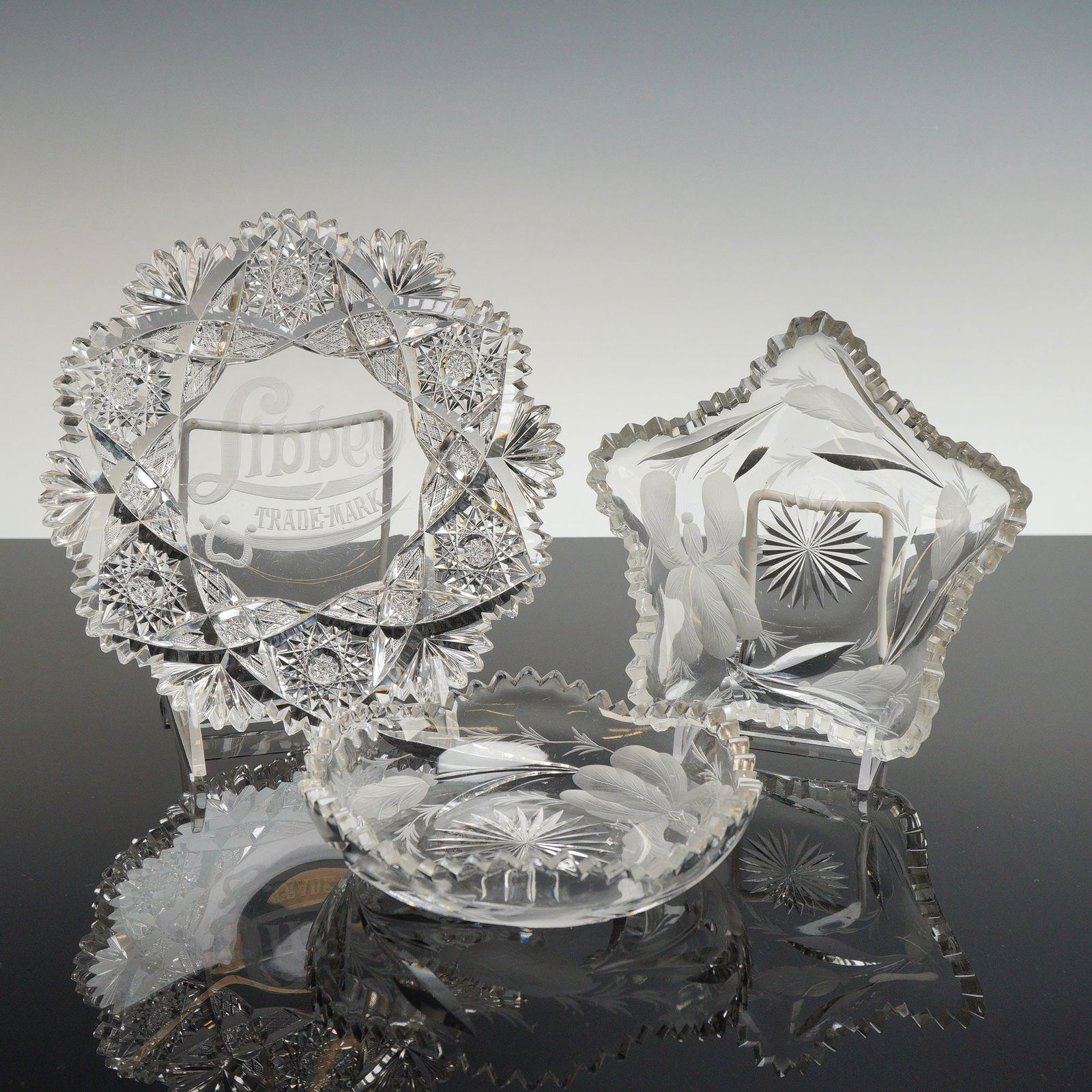 3pc Cut Crystal Candy Dishes Including Libbey and Hawkes: This trio of American Brilliant Period cut glass candy dishes includes pieces by Libbey and Hawkes. One circular dish is decorated with deep-cut hobstar and miter patterns and bears a prominent acid-e
