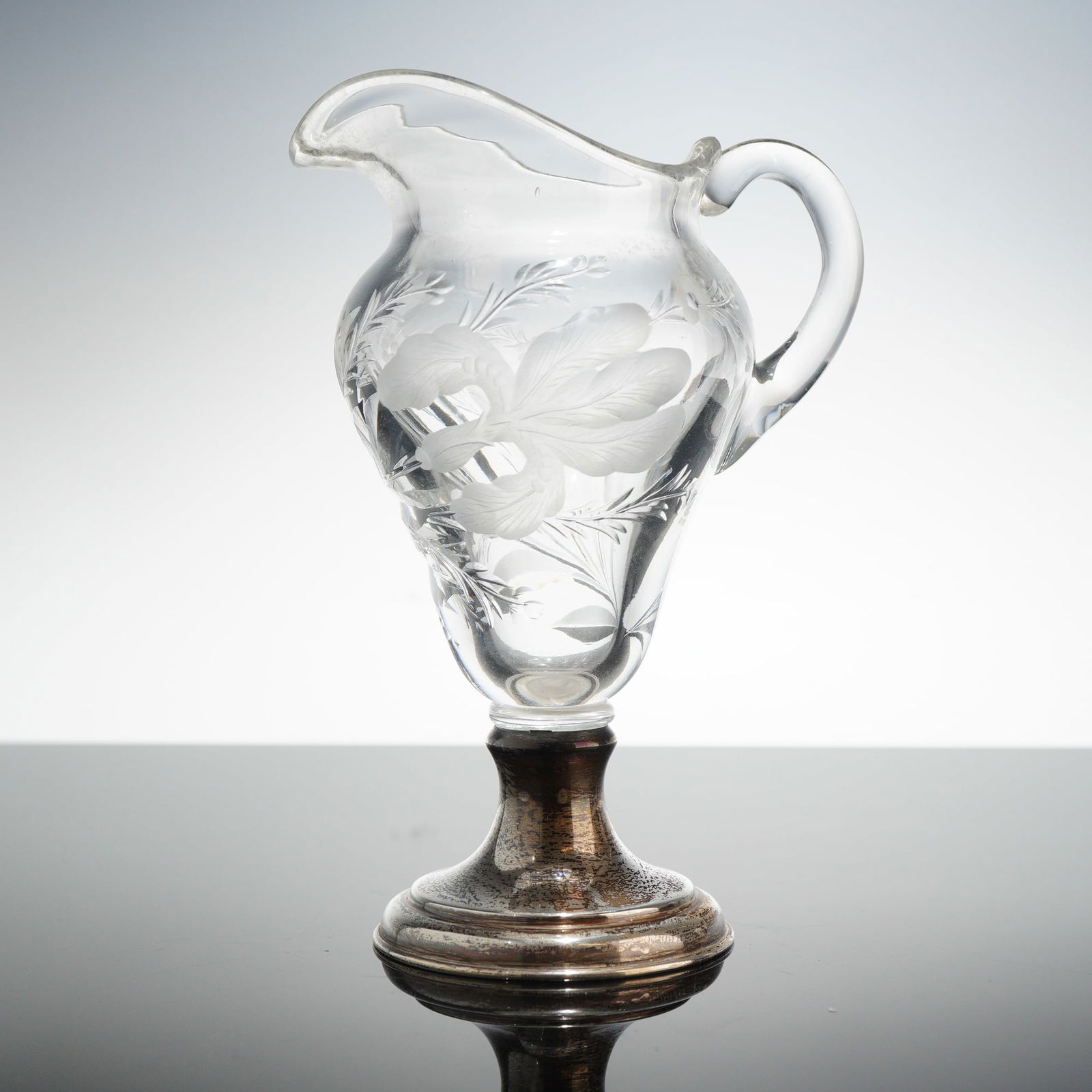 Hawkes Cut Crystal Etched Jug with Sterling Silver Base: This Hawkes cut crystal etched jug with sterling silver base features a clear glass body decorated with intaglio wheel-cut and acid-etched floral and foliate motifs, including an iris pattern. The ves