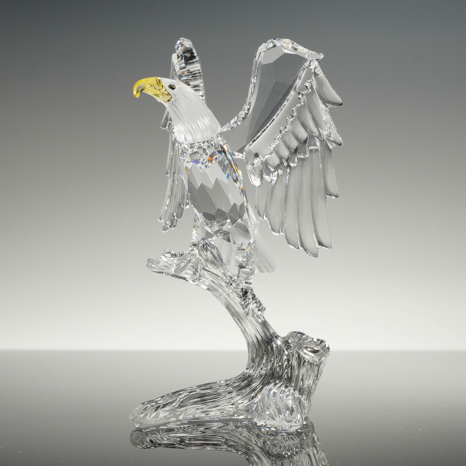 Swarovski Crystal Bald Eagle Figurine: Swarovski crystal figurine of a bald eagle, model number 7670 NR, from the Feathered Beauties collection. The piece features a faceted clear crystal body and wings, perched upon a stylized branch-like