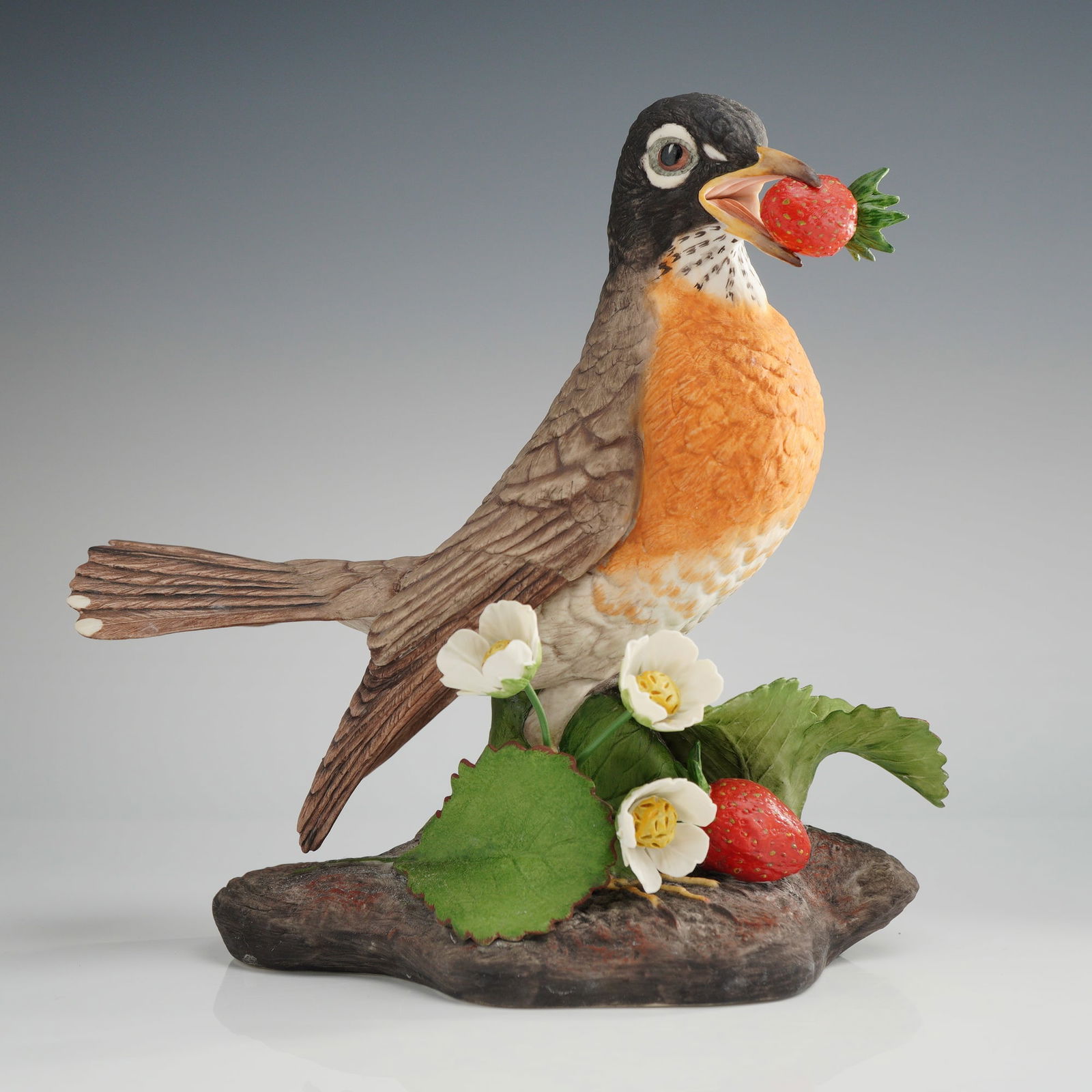 Boehm Porcelain Figurine, Robin 40201: This Boehm bisque bird figurine depicts an American Robin. The hand-painted porcelain piece features a matte finish with feather detailing and lifelike coloration. The robin is portrayed with an open